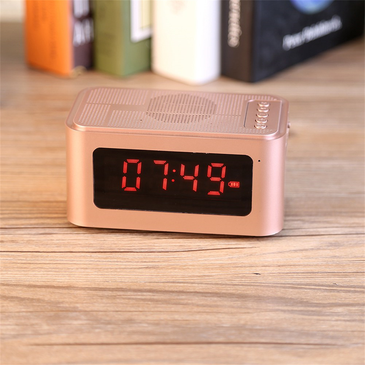 Roségoldfarbener Lautsprecher mit roter Digitaluhr, die 07:49 auf einem Holztisch anzeigt.