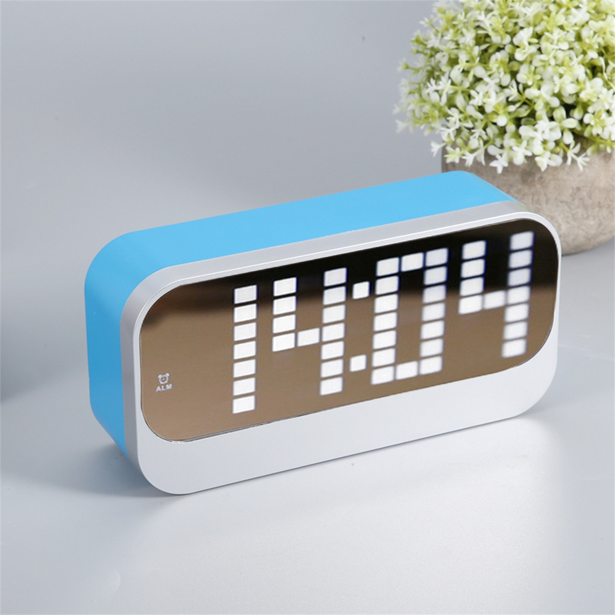 Ein blauer Wecker mit digitaler Anzeige, die 14:04 zeigt, auf einer weißen Oberfläche.