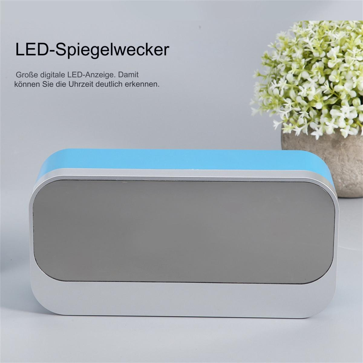 Blauer und silberner LED-Wecker, Blumen im Topf, auf heller Oberfläche.