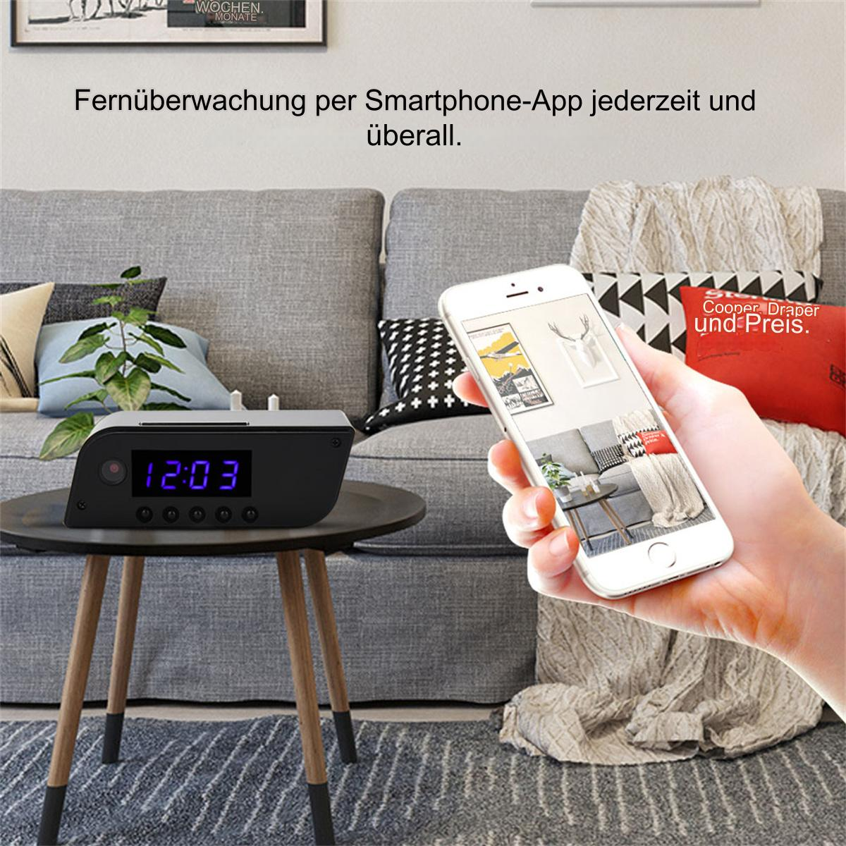 Eine Person hält ein Smartphone mit Raumansicht, ein kleiner Wecker steht auf einem Tisch.