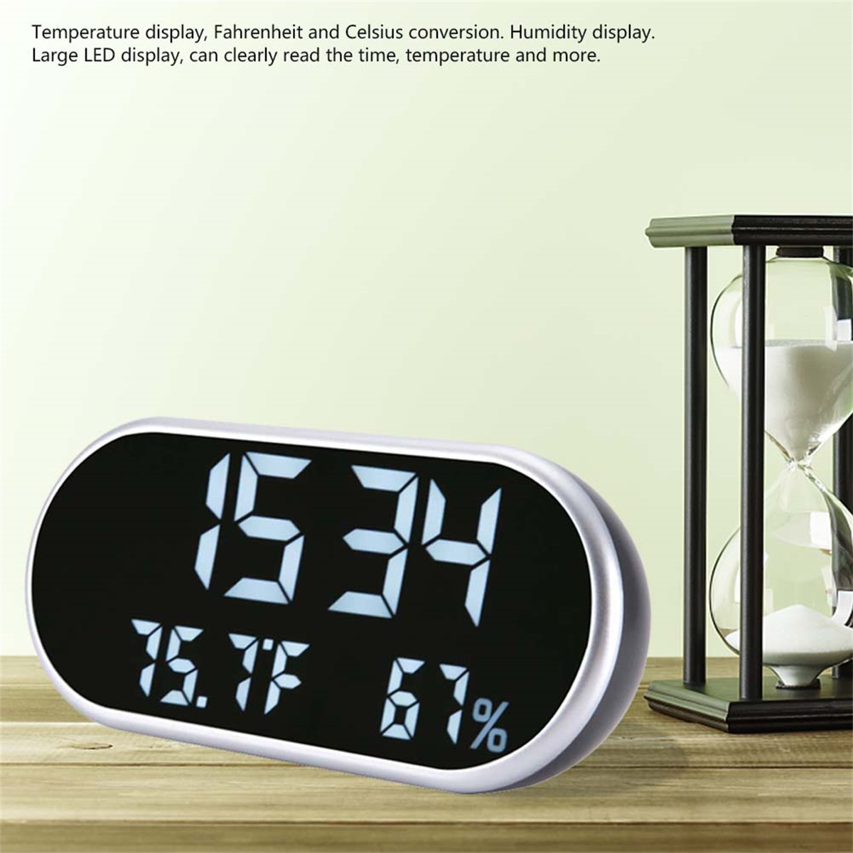 Digitaluhr zeigt Zeit, Temperatur und Luftfeuchtigkeit. Weißes Gehäuse, schwarzer Bildschirm. Holztisch.
