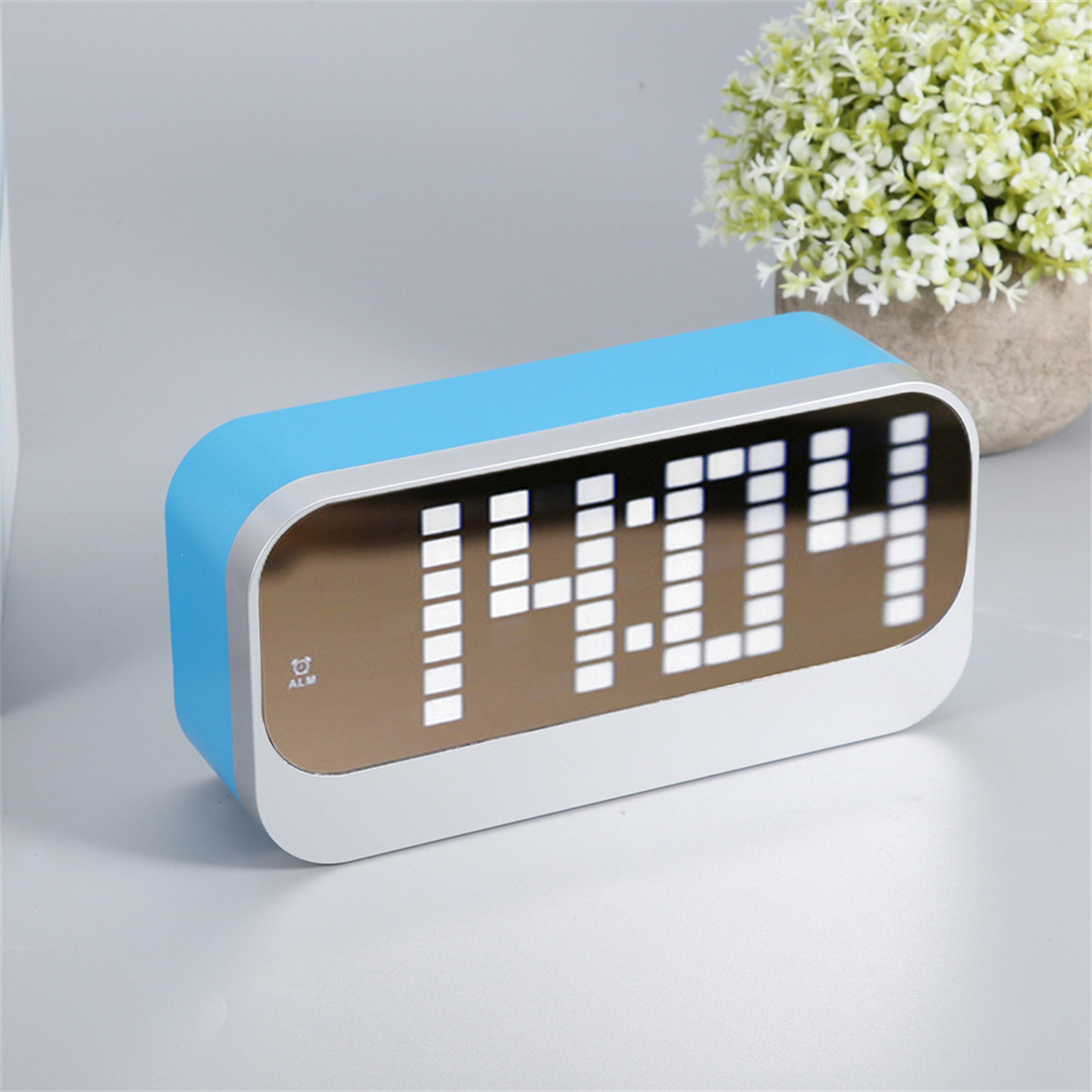 Blaue und weiße Digitaluhr mit der Anzeige 14:04 auf einer weißen Oberfläche.