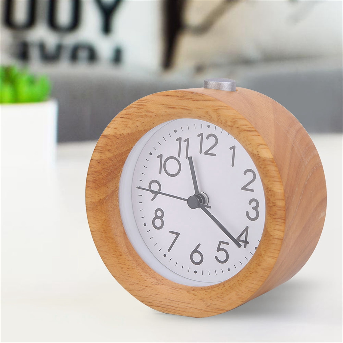 Wecker aus Holz auf weißer Oberfläche. Ziffernblatt zeigt die Uhrzeit.
