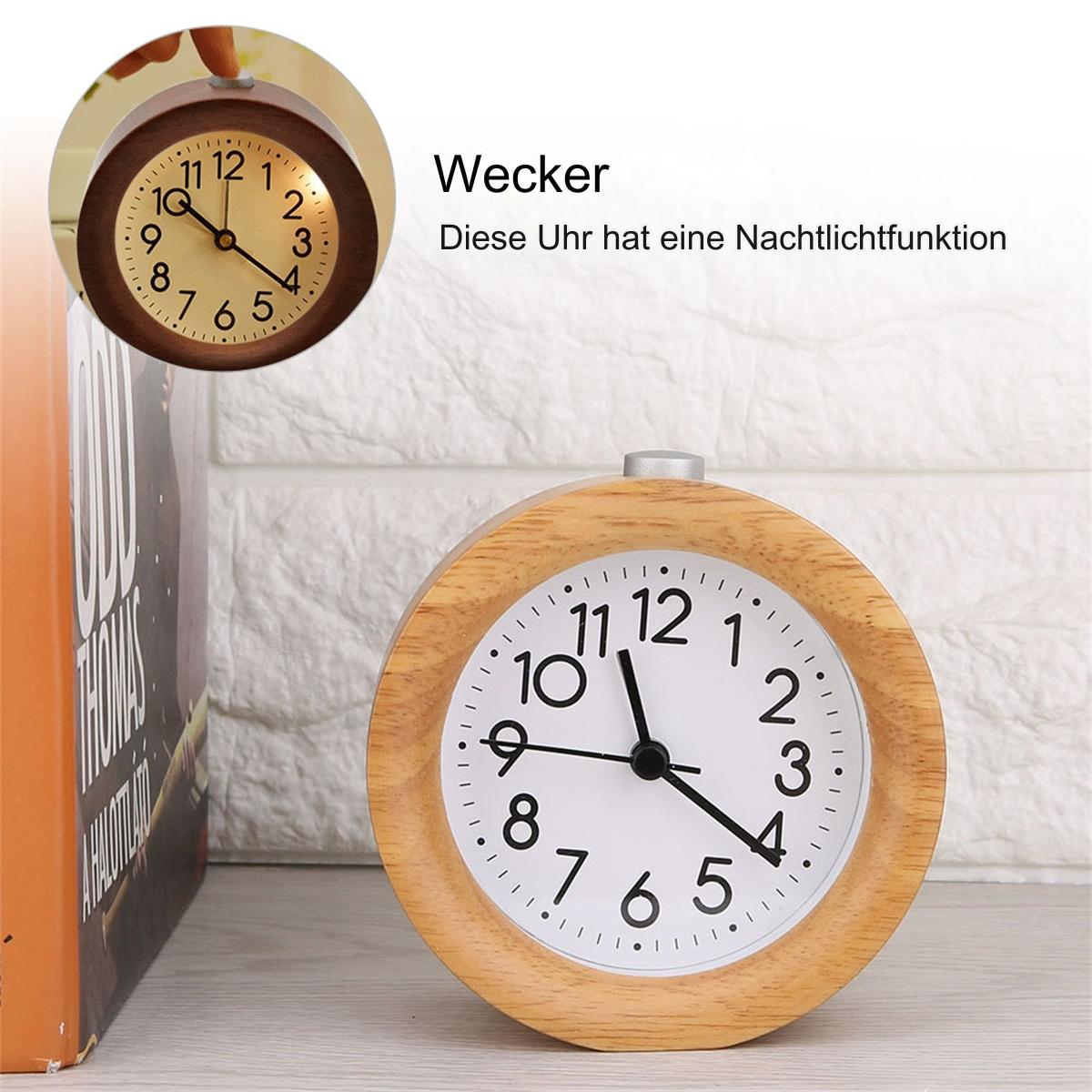Eine Holzuhr mit schwarzem Zifferblatt und eine kleinere Uhr oben links. Sie steht vor einer weißen Backsteinmauer.