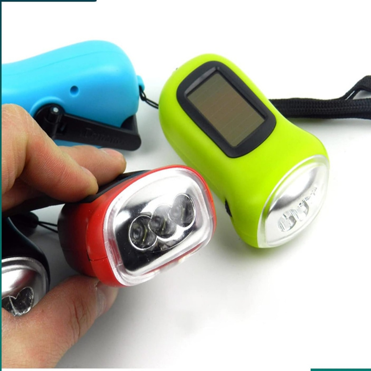 Hand hält eine rote Taschenlampe, neben einer grünen und einer blauen Taschenlampe.