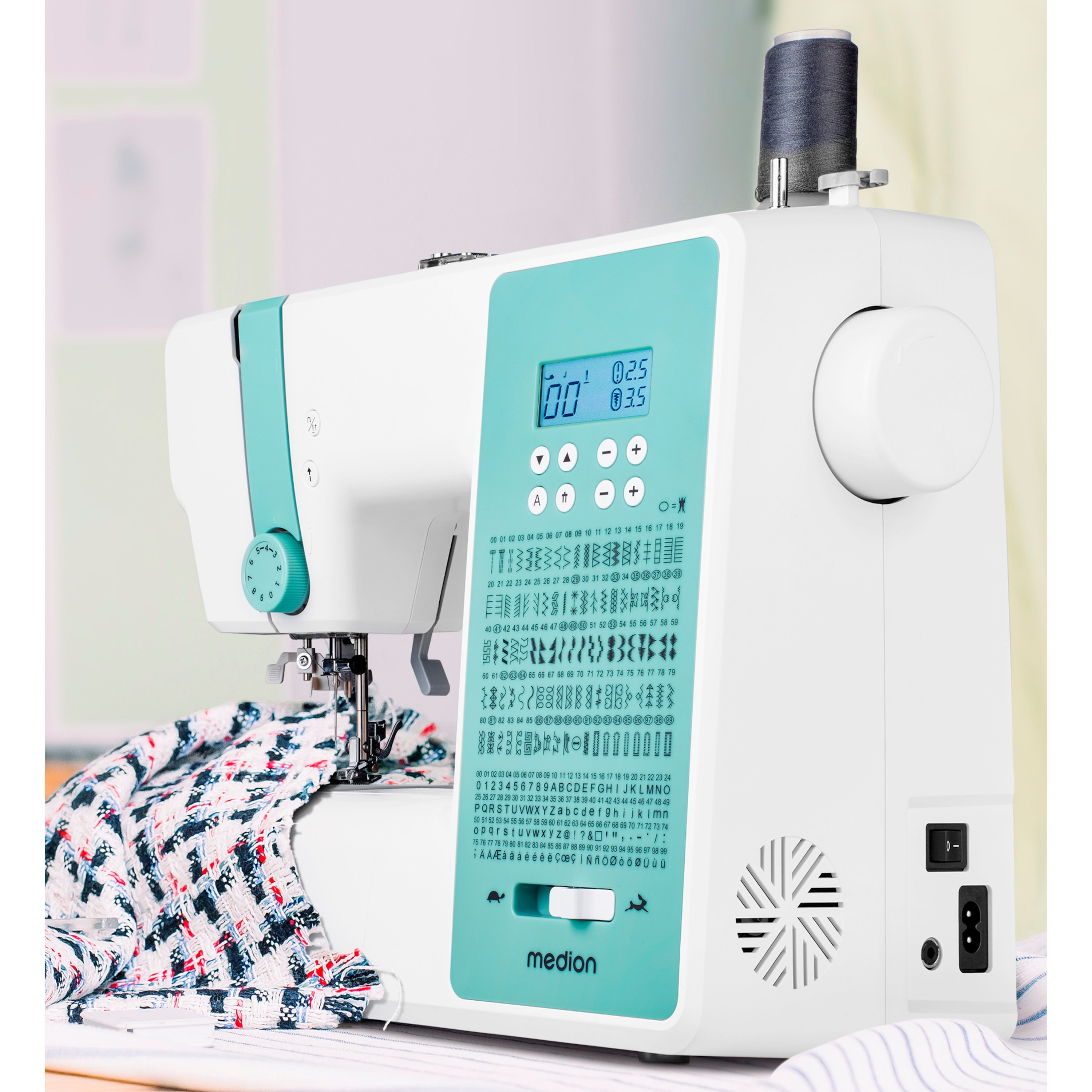 Biała i turkusowa maszyna do szycia z wyświetlaczem cyfrowym, podawany materiał. Widoczne przyciski i cyfry.