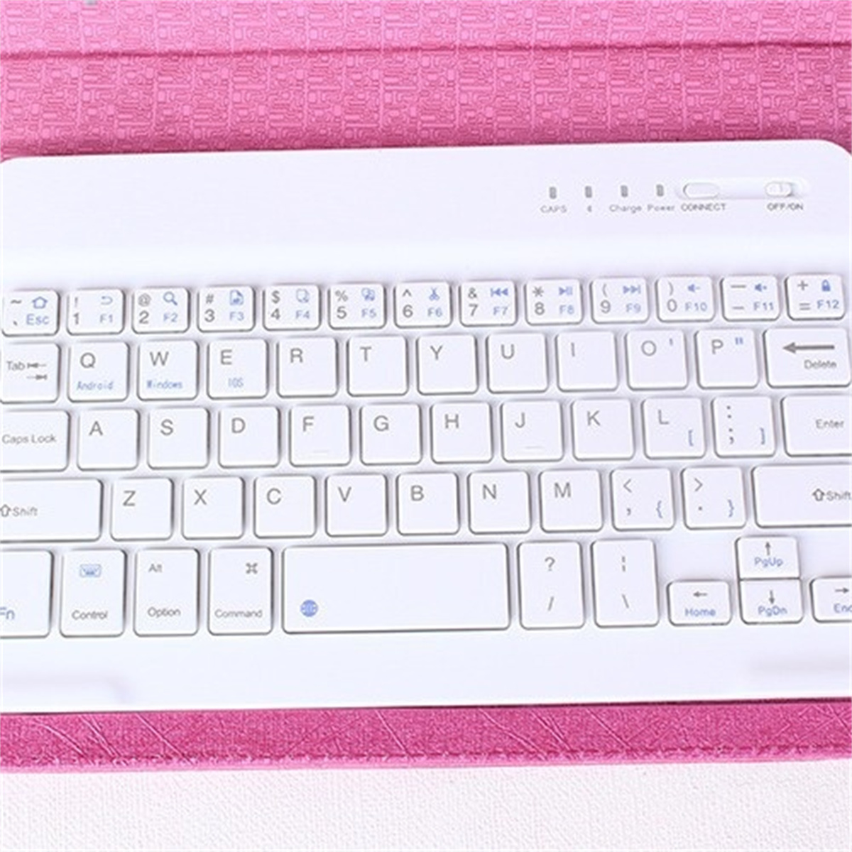 Weiße kabellose Tastatur auf einer rosa Oberfläche. Sie hat viele Tasten mit Symbolen und Zeichen.