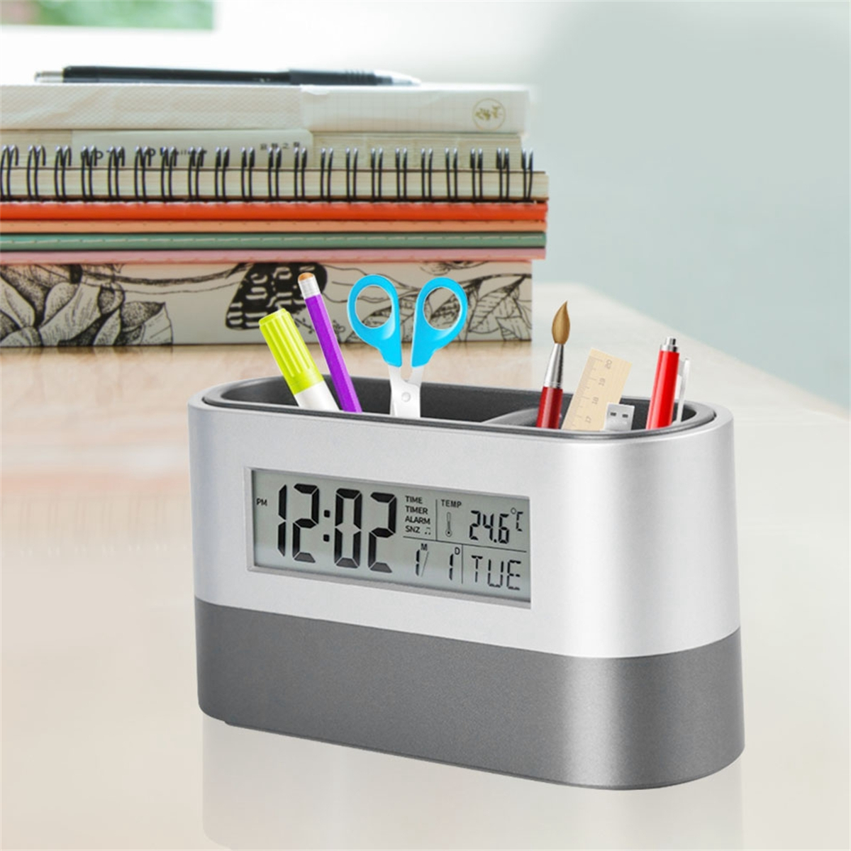 Ein Schreibtisch-Organizer mit Digitaluhr. Er enthält Stifte, Bleistifte, Scheren und einen Pinsel.