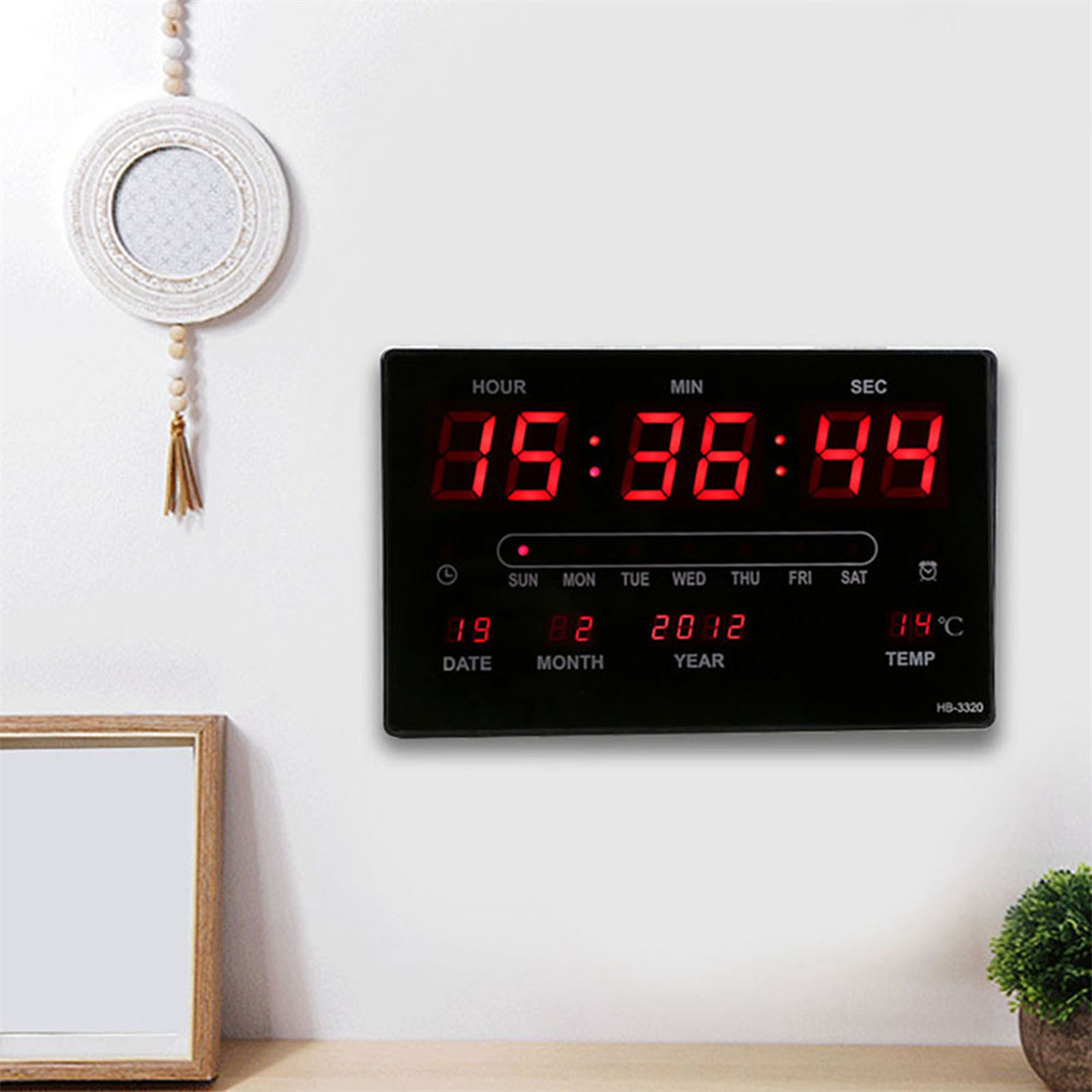 Digitaluhr. Rote Zahlen. Zeigt Zeit, Datum und Temperatur an. Schwarzer Rahmen. Weißer Hintergrund.