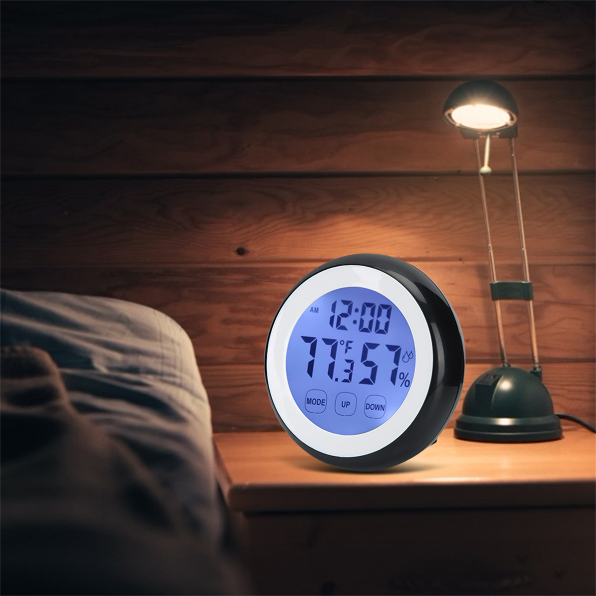Eine Digitaluhr und eine Lampe auf einem Nachttisch. Ein Bett ist im Hintergrund sichtbar.