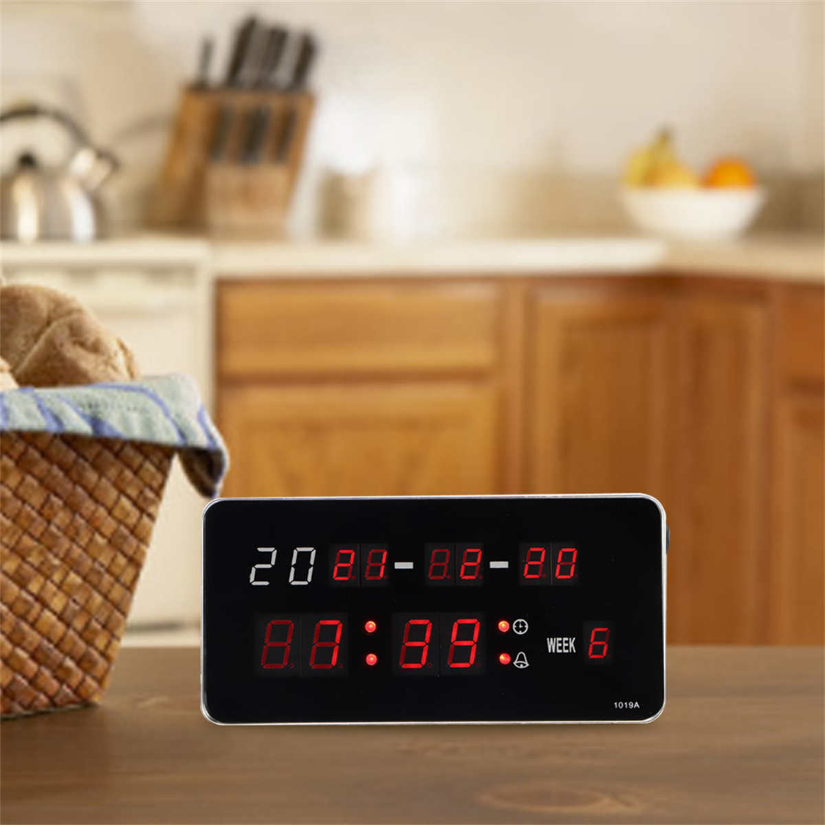 Digitaluhr mit Anzeige von Uhrzeit und Datum. Küchenhintergrund, Holztisch. Rote Zahlen auf Schwarz.