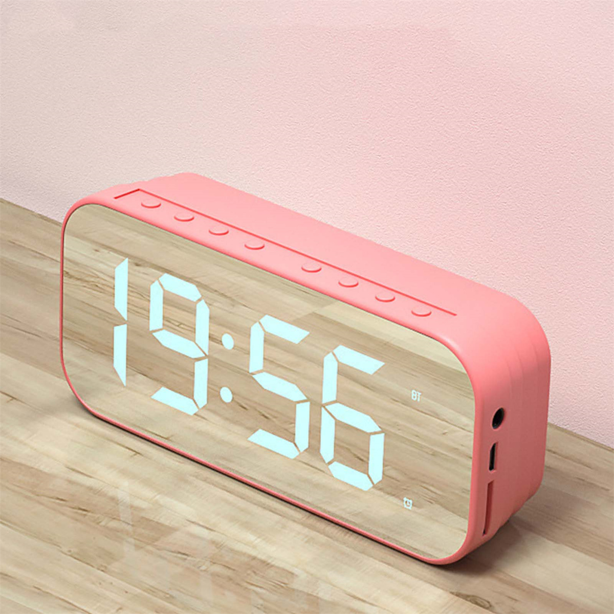 Rosa Digitaluhr mit Anzeige 19:56. Die Uhr hat eine verspiegelte Oberfläche und Lautsprecher.