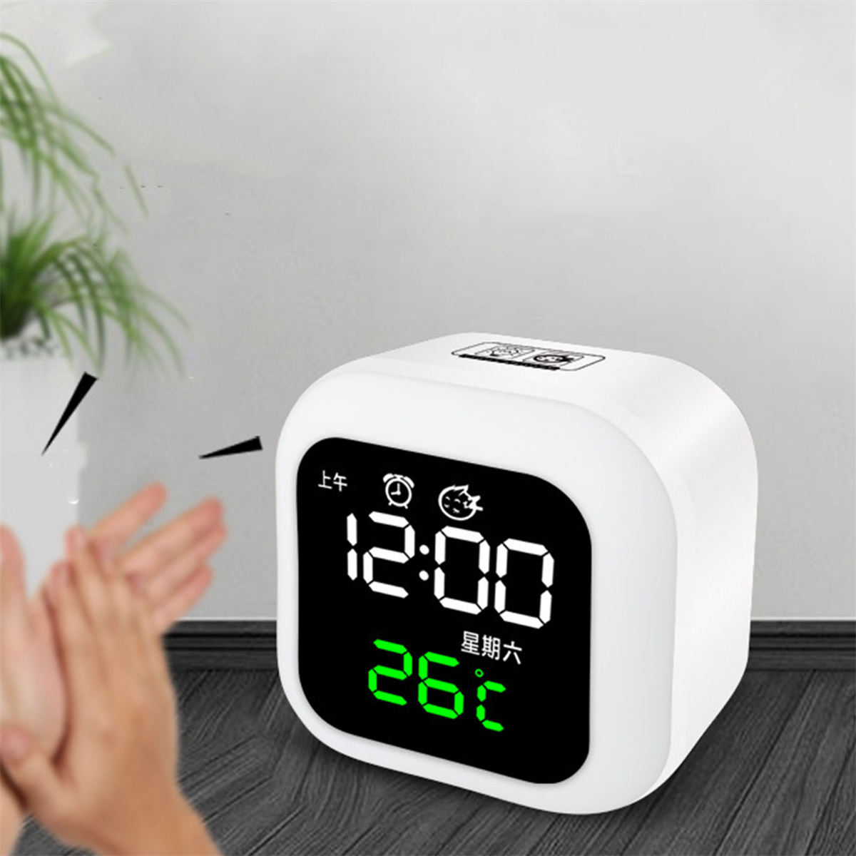 Weißer digitaler Wecker mit Uhrzeit und Temperatur. Eine Hand klatscht gleich.