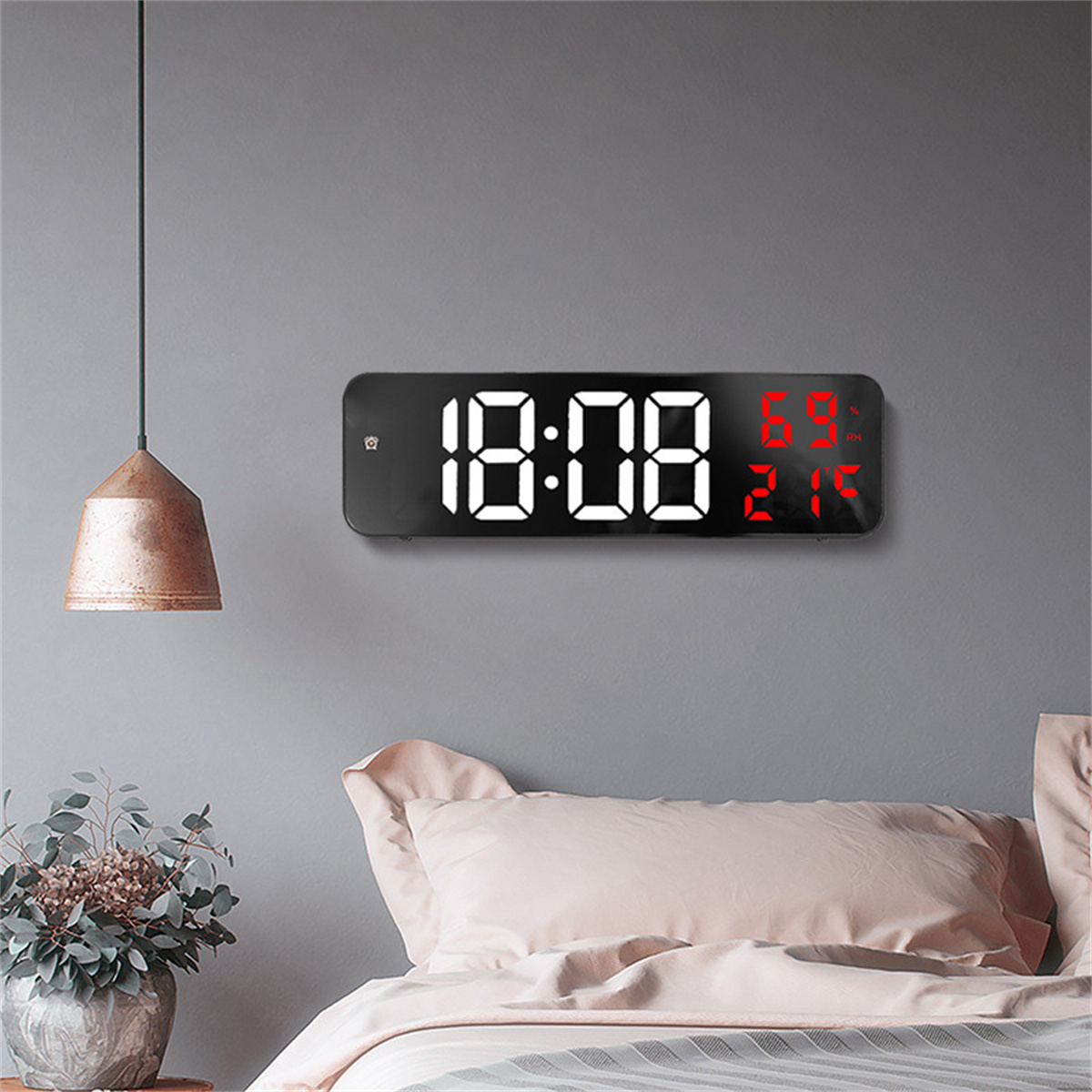 Digitaluhr mit Zeit und Temperatur, an grauer Wand, mit Hängelampe.
