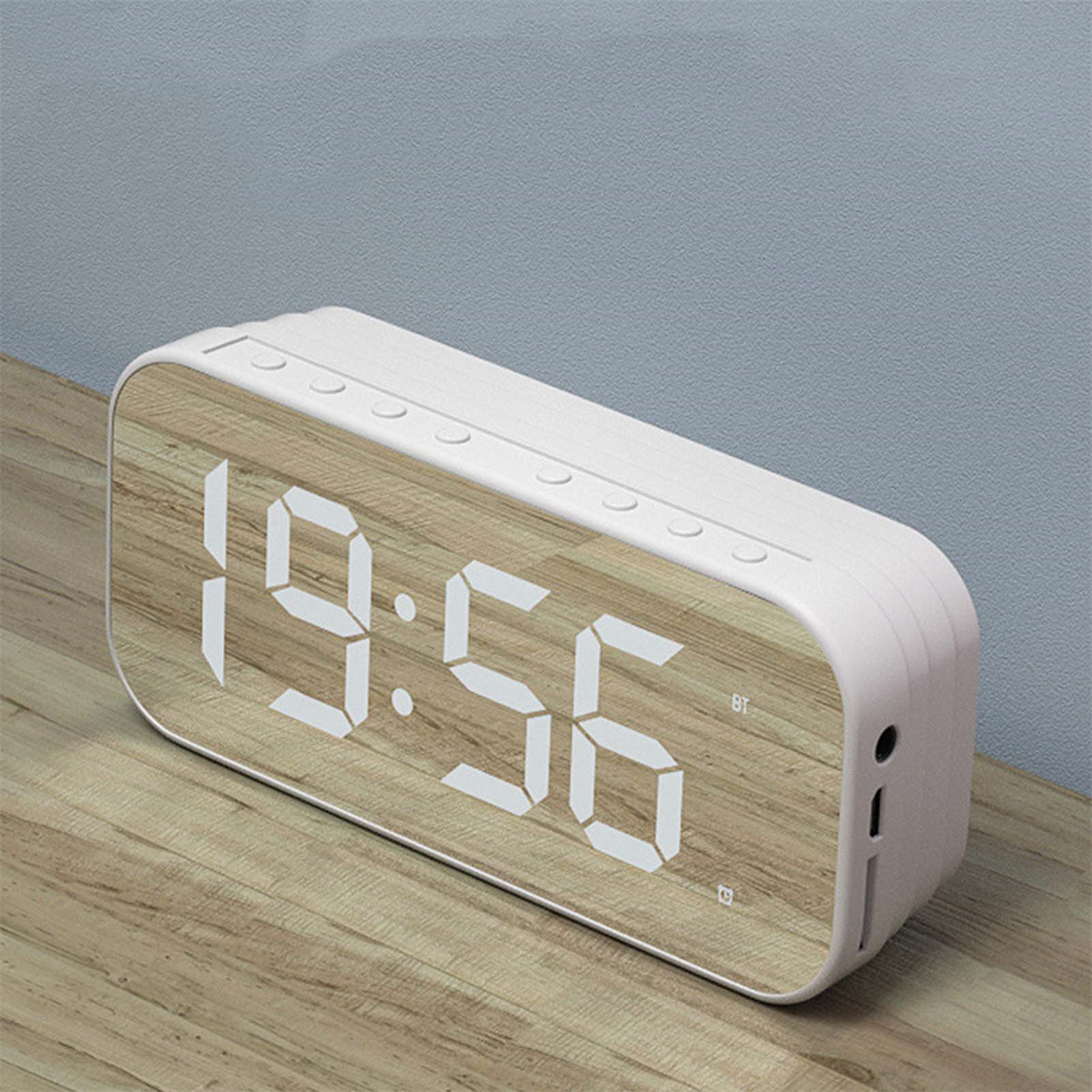 Weiße Digitaluhr mit Holzmaserung. Zeigt 19:56 an. Hat Knöpfe und Anschlüsse.