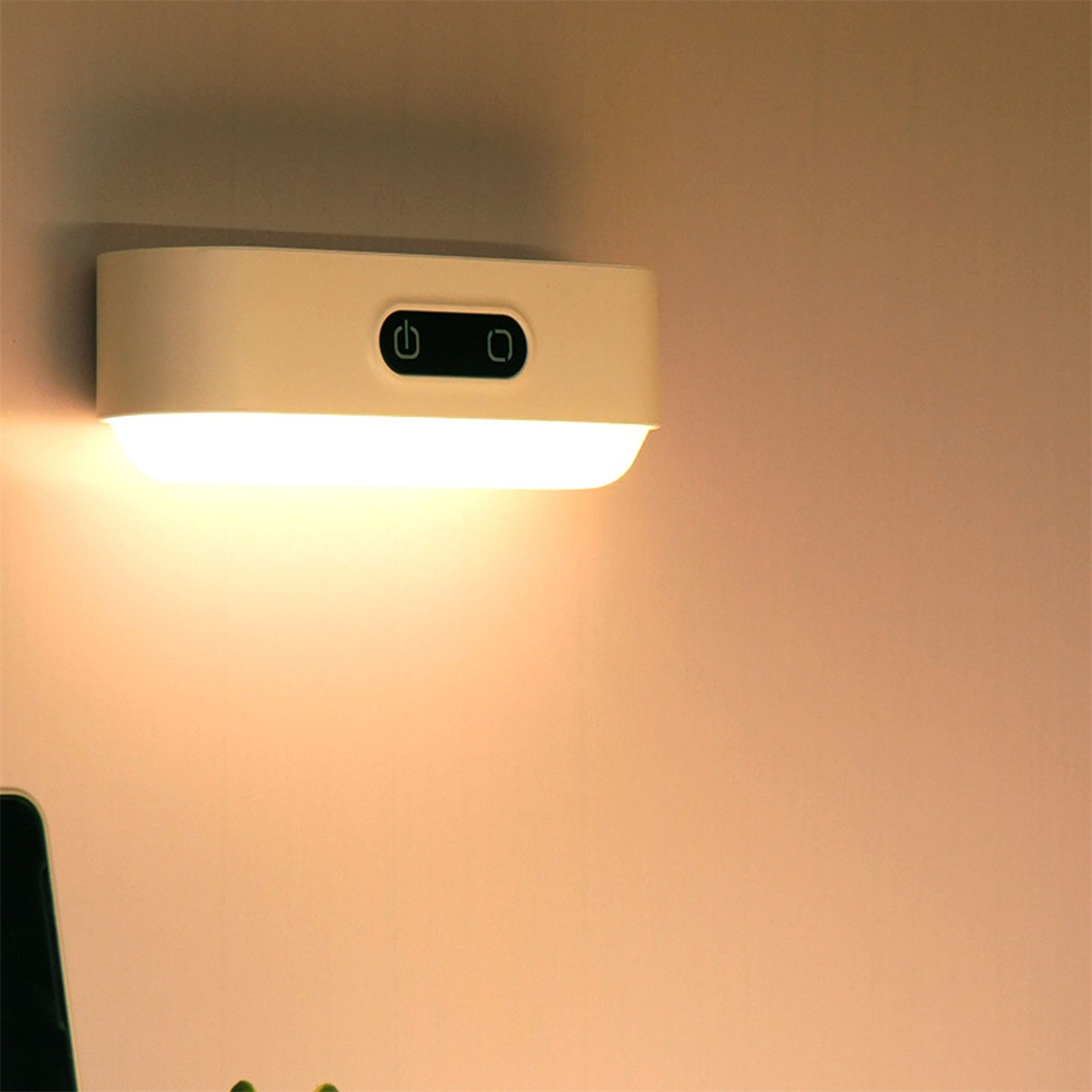Eine an der Wand montierte, weiße, rechteckige Lampe, die ein warmes Licht ausstrahlt. Zwei schwarze Knöpfe.