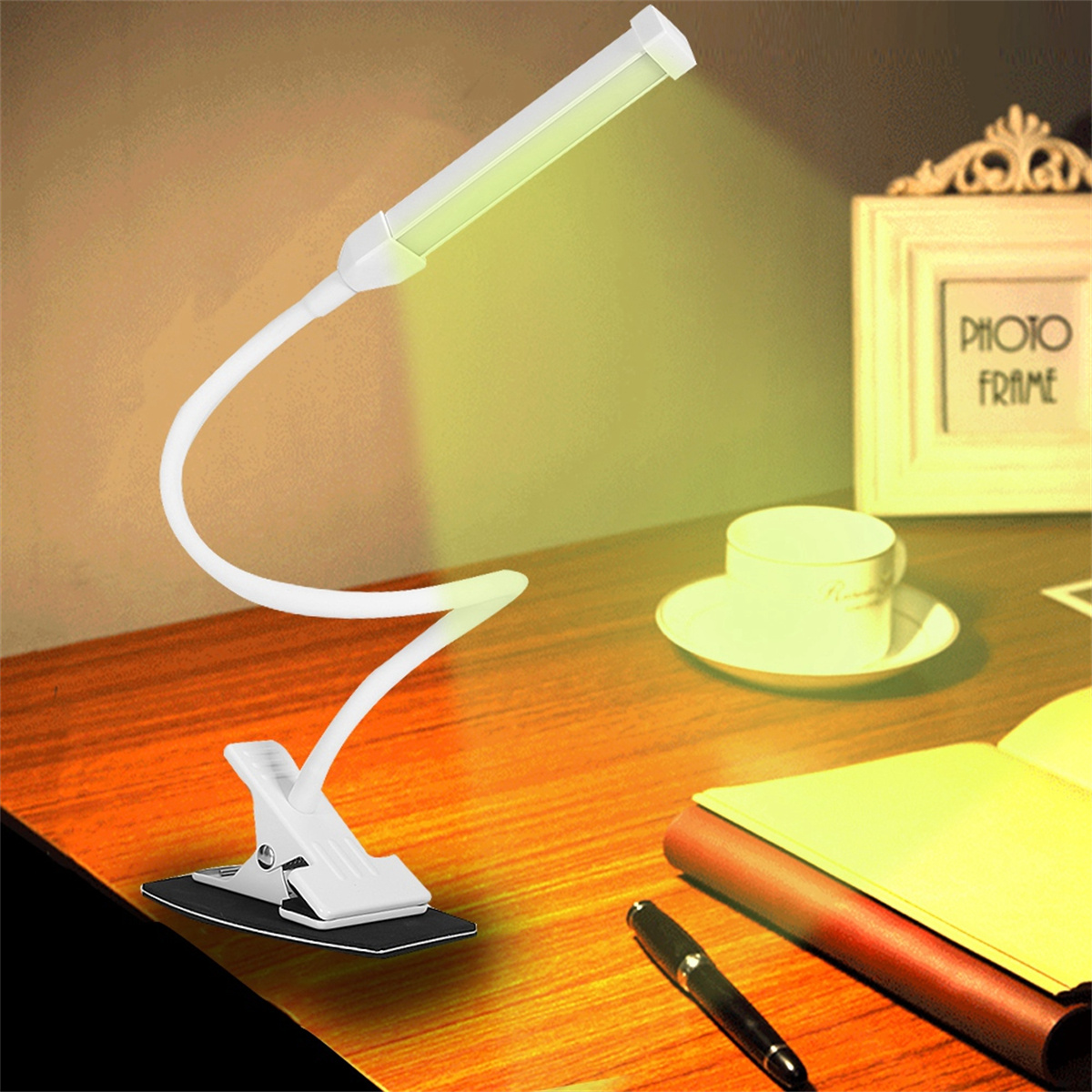 Eine flexible weiße Schreibtischlampe steht auf einem Holzschreibtisch. Es gibt einen Stift, einen Bilderrahmen und eine Tasse mit Untertasse.