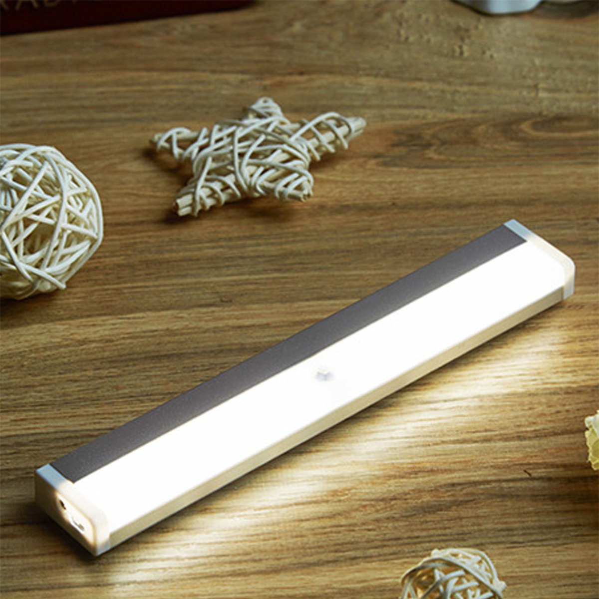 Silberne und weiße LED-Lichtleiste auf Holzoberfläche, mit Dekoration.