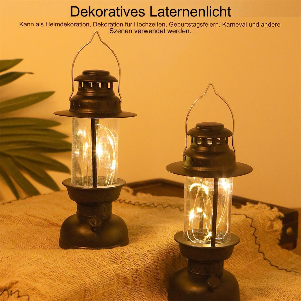 Zwei dekorative Laternen mit Lichtern im Inneren, auf einem Tisch platziert.