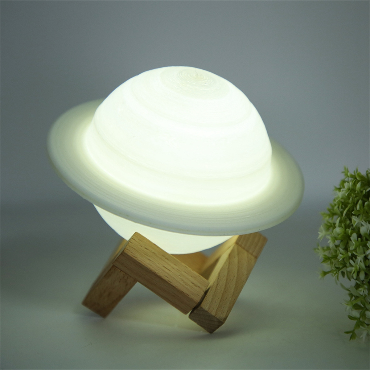 Eine Saturnförmige Lampe auf einem Holzständer, leuchtet hell.