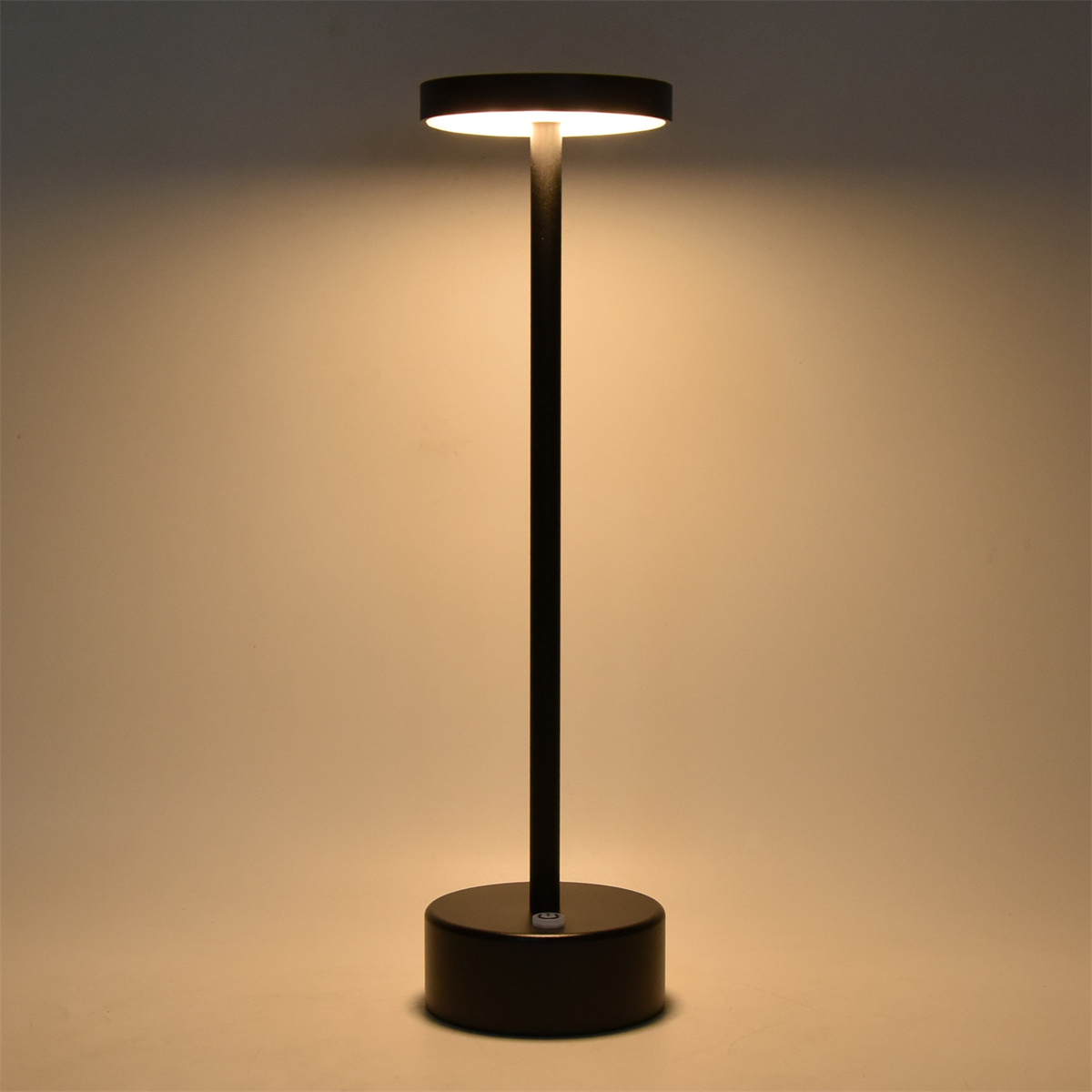 Schwarze, hohe, minimalistische Lampe mit rundem Kopf, auf hellem Hintergrund.