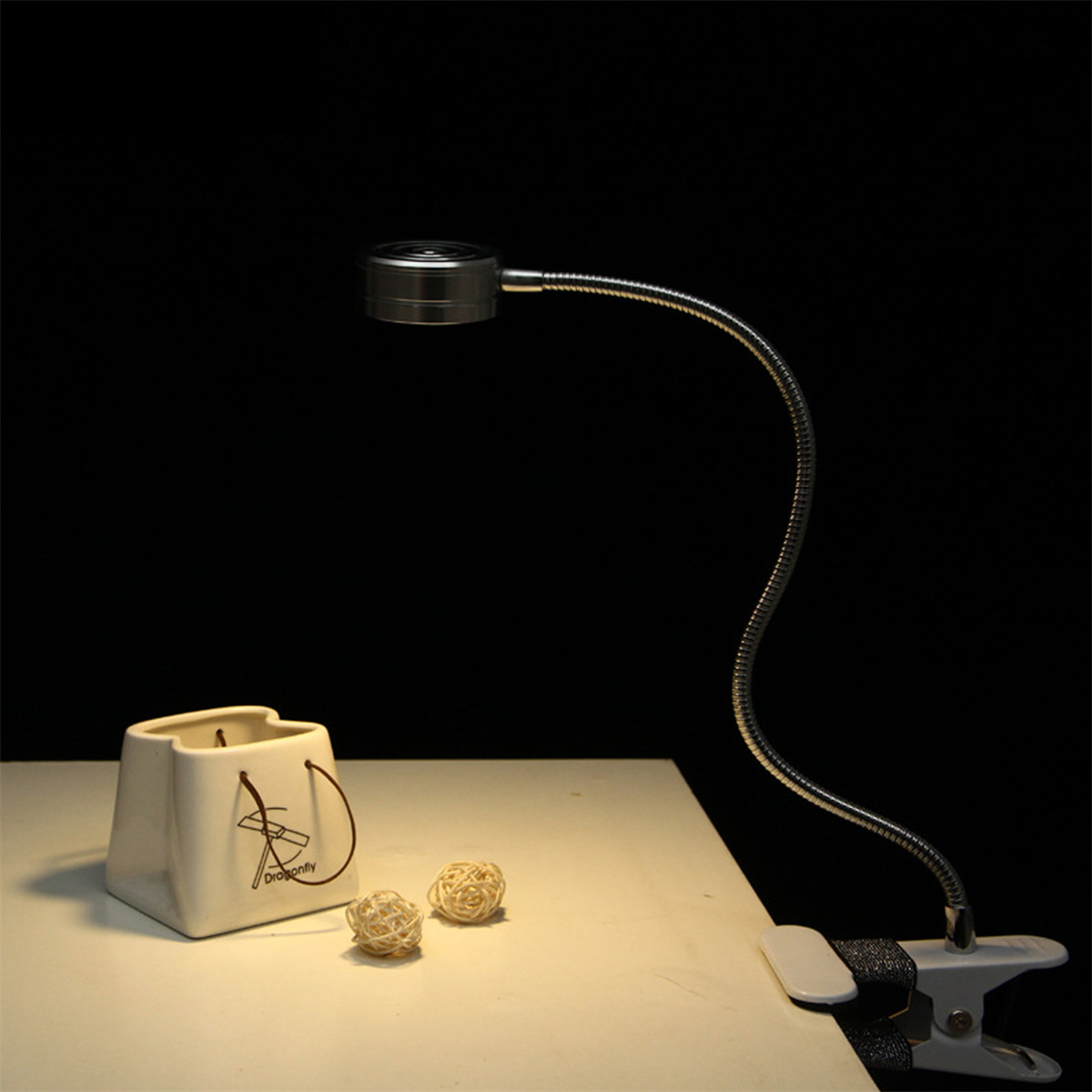 Flexible Lampe auf einem Tisch. Keramiktopf mit zwei dekorativen Kugeln. Dunkler Hintergrund.