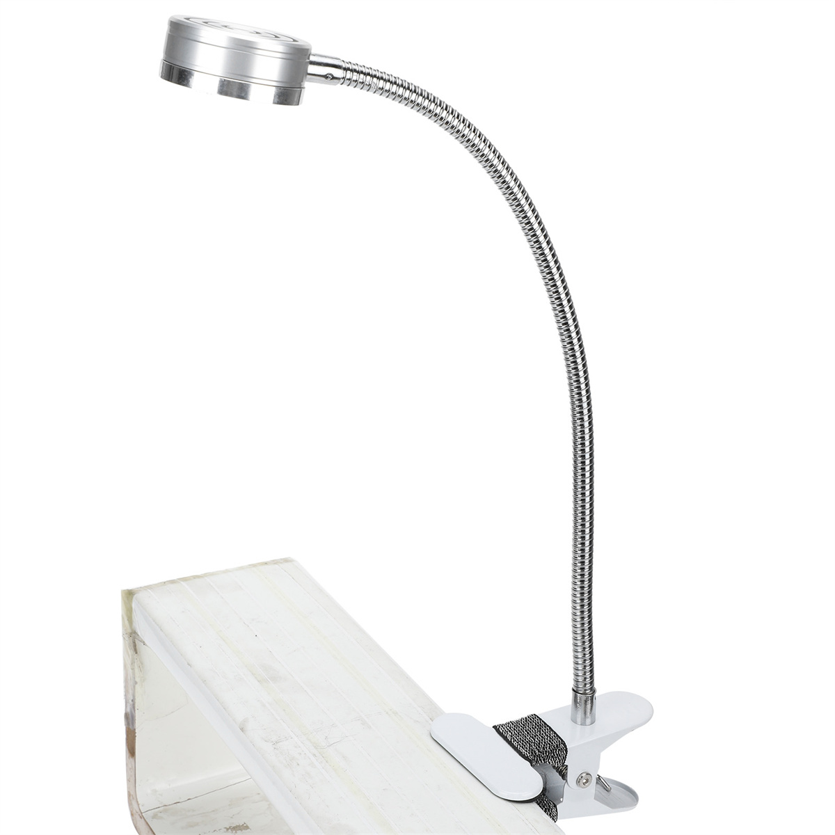Eine silberne, flexible Schreibtischlampe, die an einer weiß lackierten Holzoberfläche befestigt ist. Weißer Hintergrund.
