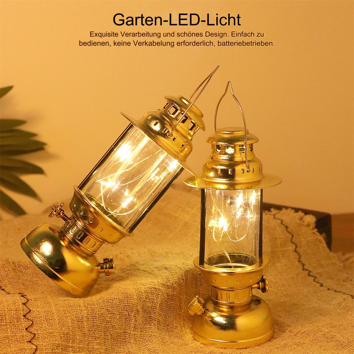 Zwei goldene Laternen mit einem Zylinder und einem Griff aus Glas. Sie stehen auf einer strukturierten Oberfläche.