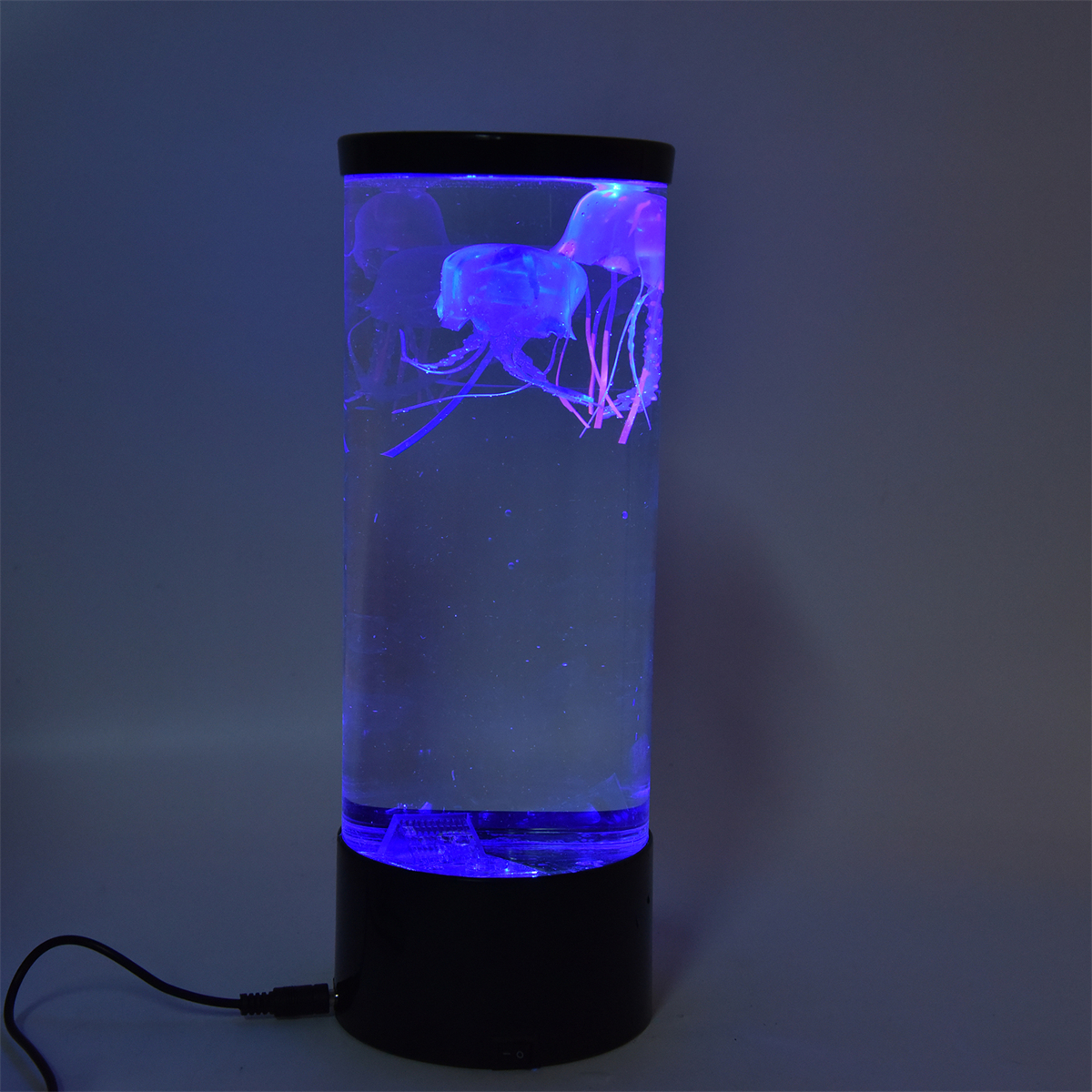 Zylinderförmige Lampe mit Quallen im Inneren. Das Wasser ist blau mit lila Lichtern. Der Sockel ist schwarz.