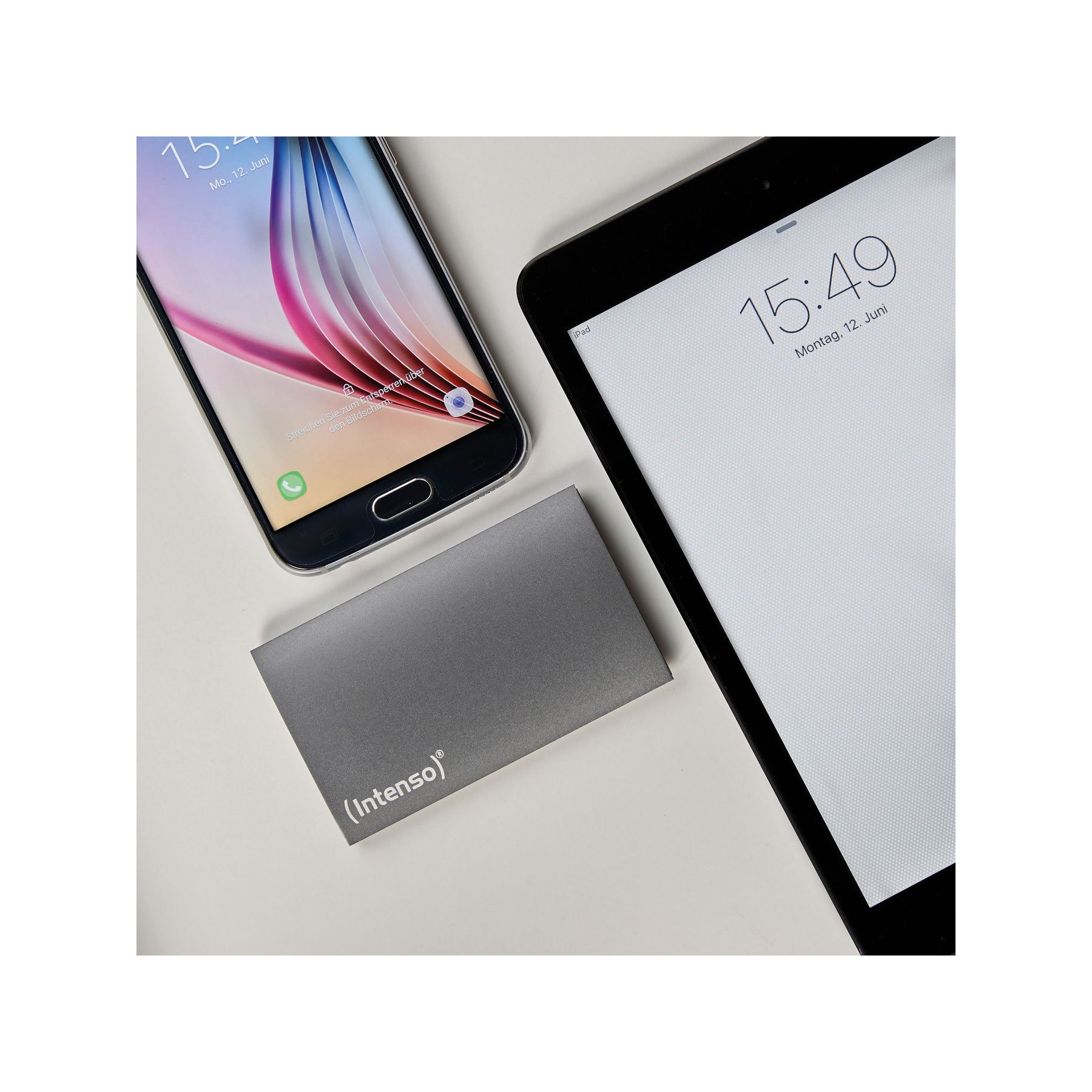 Telefon, tablet i zewnętrzny dysk twardy umieszczone na białej powierzchni.