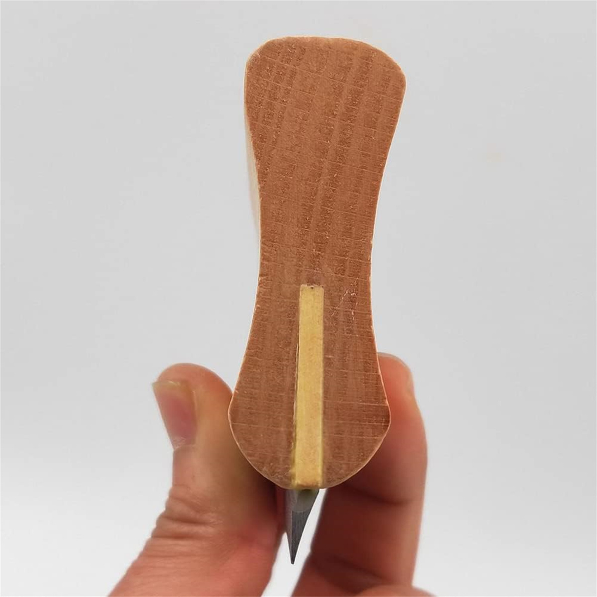 Holzschnitzwerkzeug in der Hand. Es hat eine Metallklinge.