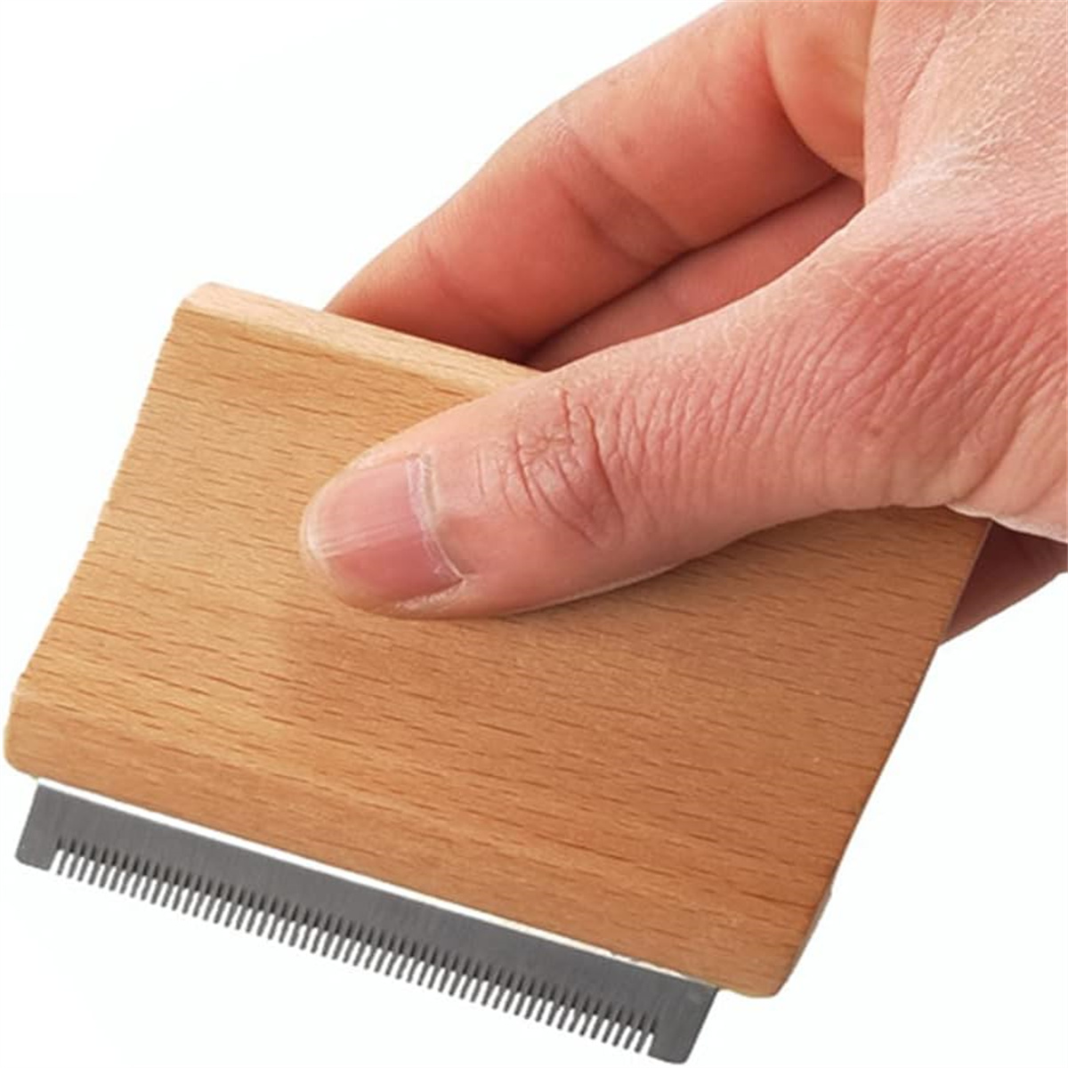 Ein hölzerner Fusselentferner mit einem Metallkamm. Eine Hand hält ihn vor weißem Hintergrund.