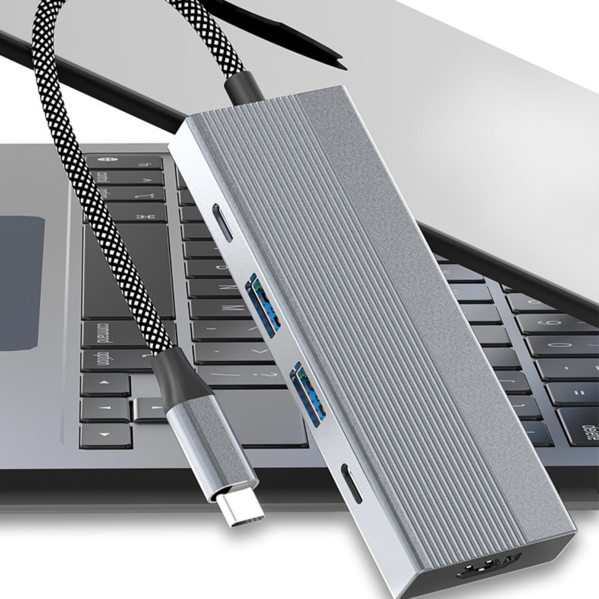 Ein silberner USB-Hub mit mehreren Anschlüssen, verbunden mit einem Laptop mit einem schwarz-grauen Kabel.