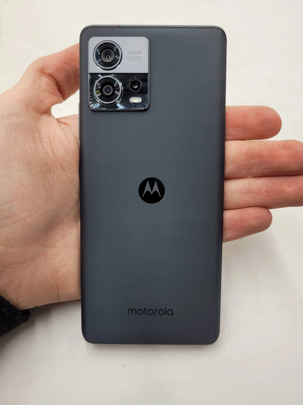 Hand, die die Rückseite eines grauen Motorola-Telefons hält.