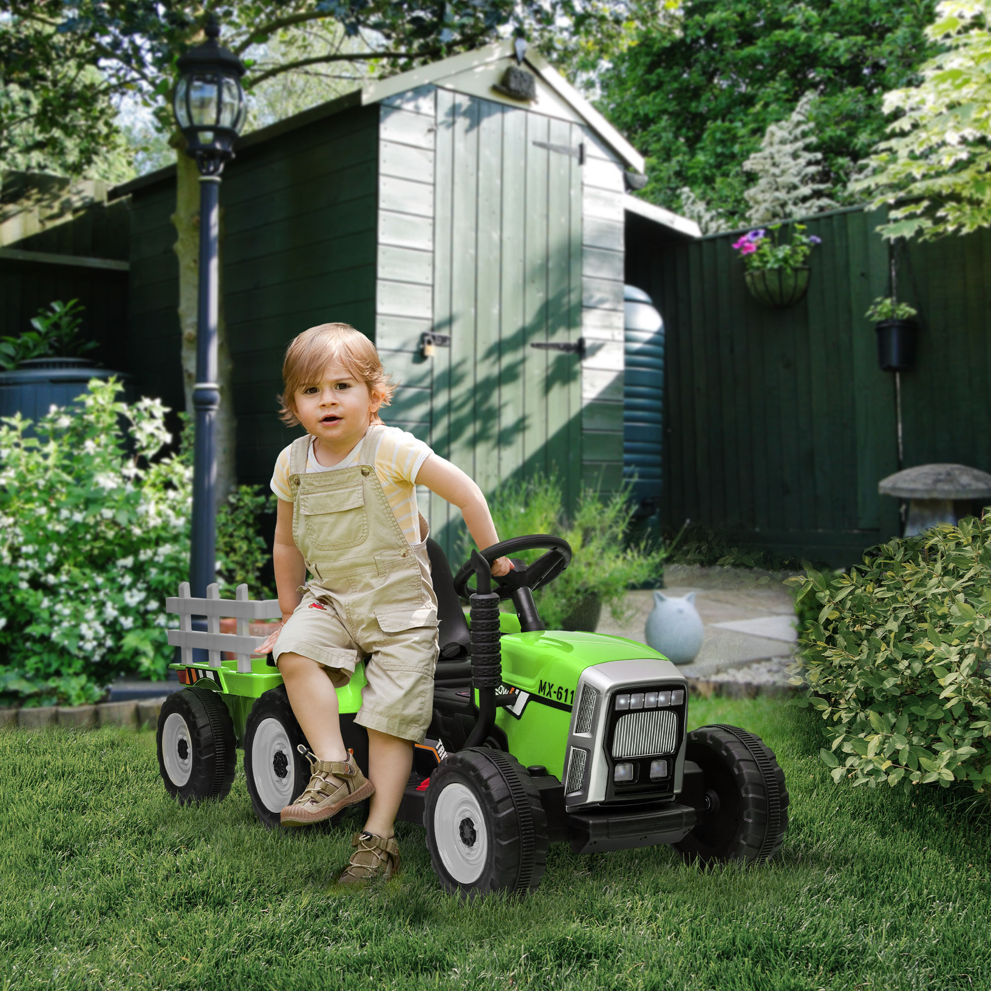 Bambino su un trattore giocattolo verde in un cortile con erba verde e un capanno.