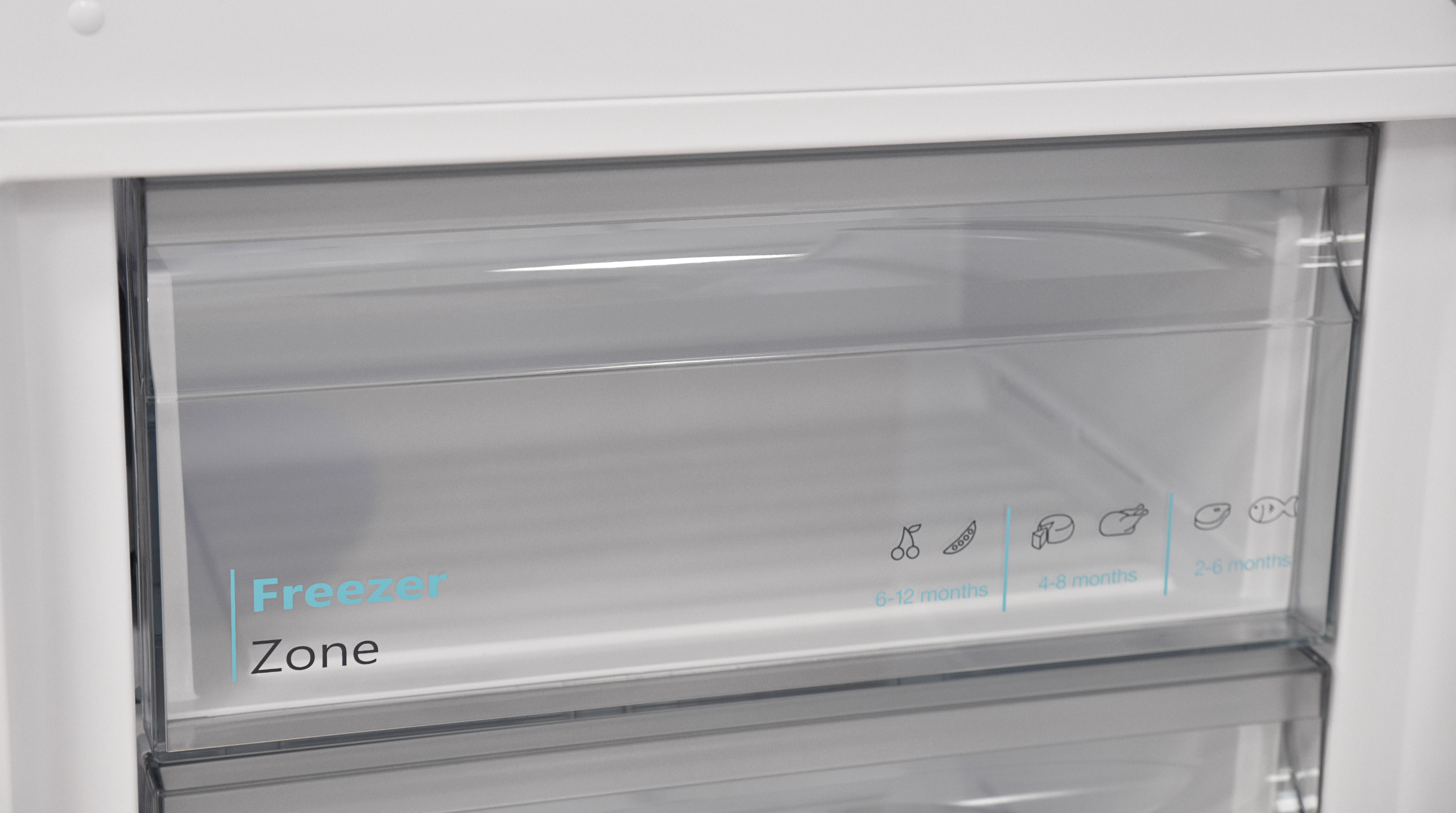 Vrieslade met 'Freezer Zone' en afbeeldingen van voedsel.