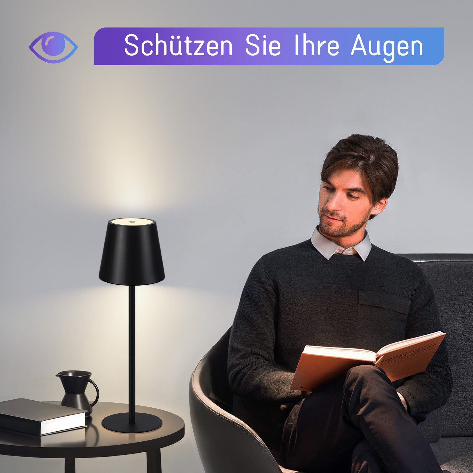 Mężczyzna czyta książkę pod czarną lampą stołową, obok czarnego kubka.