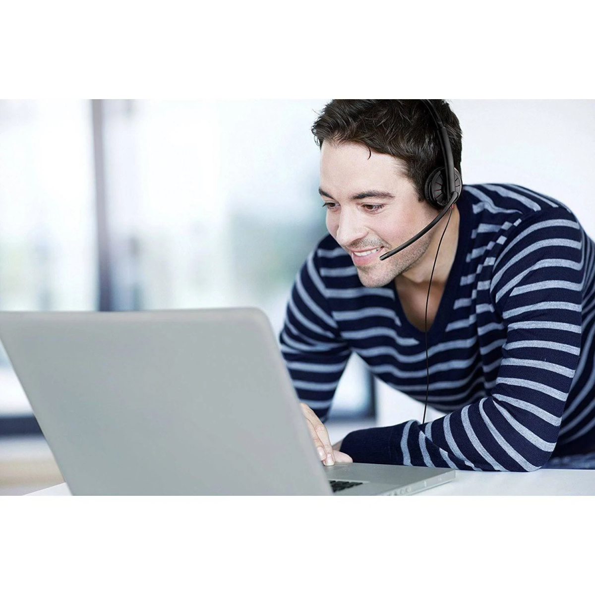 Un uomo con le cuffie, sorridente mentre guarda lo schermo di un laptop.