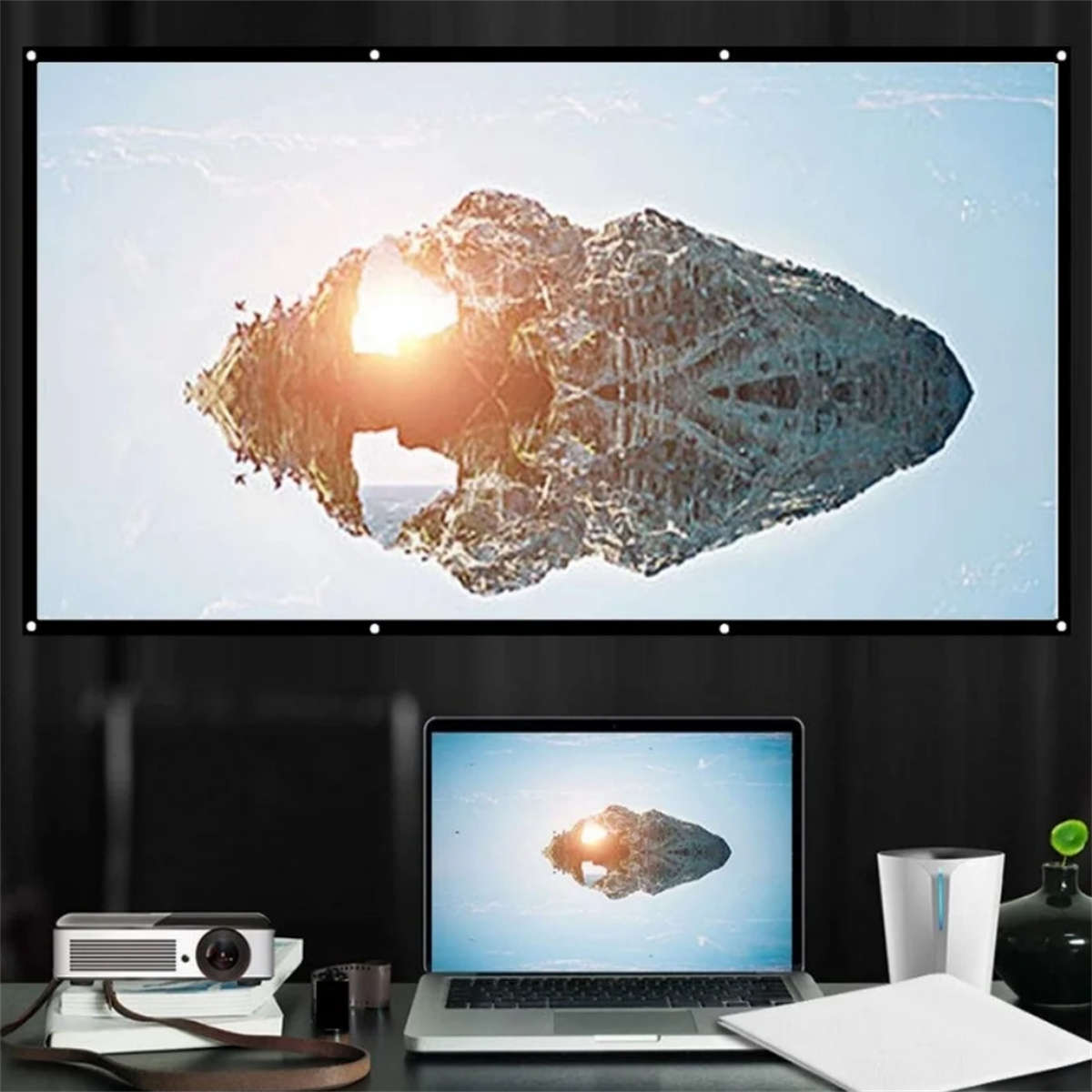 Ein Laptop und ein Projektor, die eine Landschaftsszene auf einer Leinwand in einem dunklen Raum zeigen.
