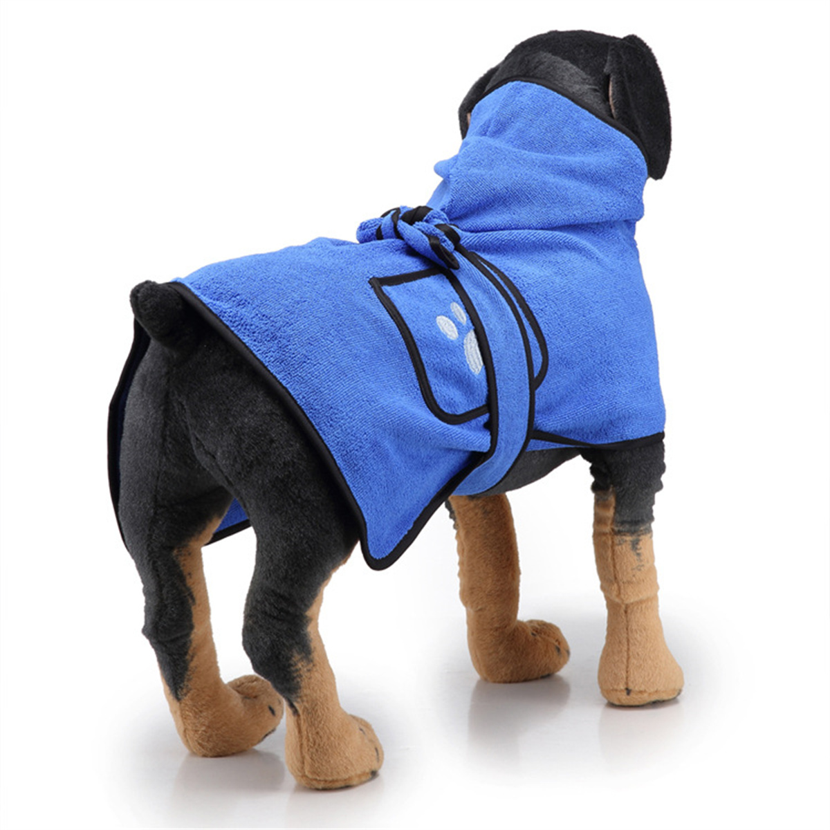 Hund trägt blauen Handtuchmantel. Schwarzer Hund mit braunen Pfoten und blauem Bademantel mit Pfotenabdruck.