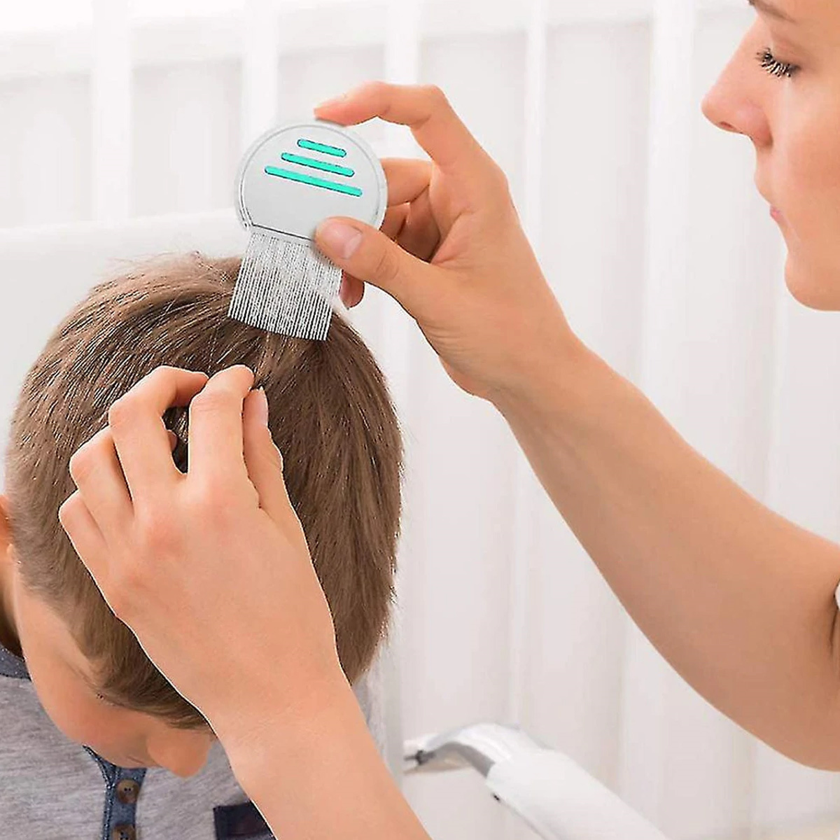 Eine Frau kämmt dem Kind die Haare mit einem Läusekamm. Das Kind ist abgewandt.