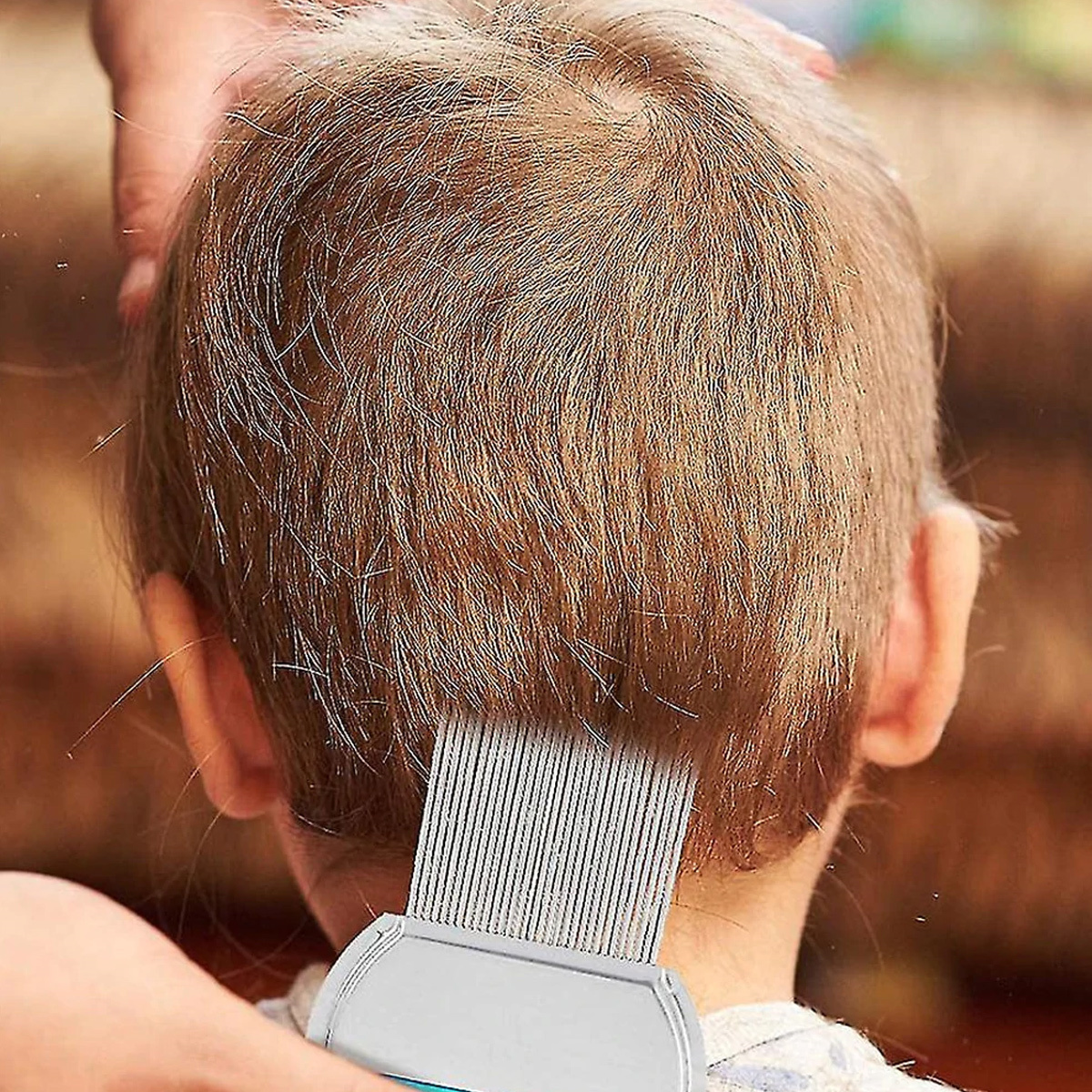 Ein Kamm entfernt Läuse aus dem Haar eines Kindes. Der Kamm ist weiß und blau.