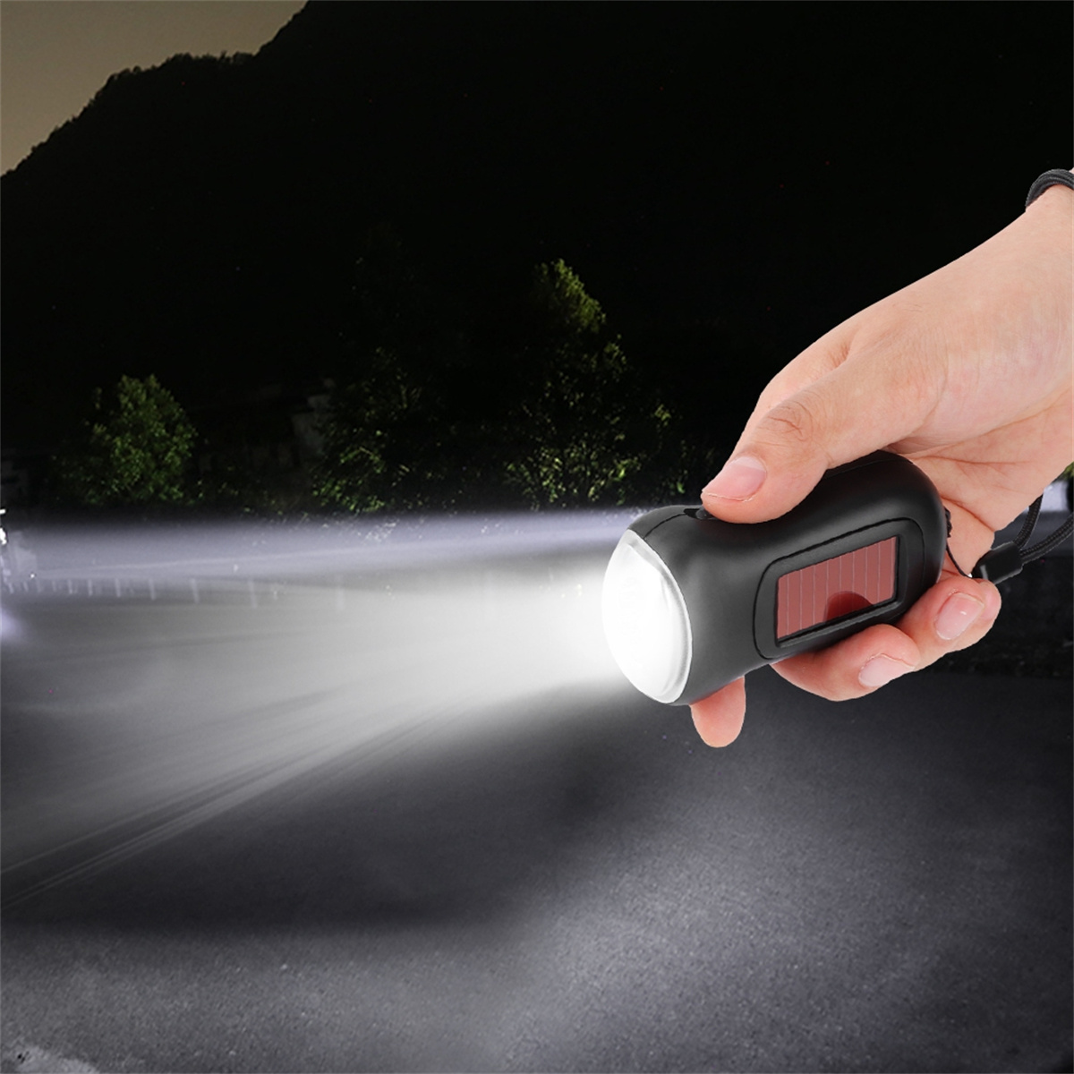 Eine Hand hält eine schwarze Taschenlampe und leuchtet einen Lichtstrahl auf eine dunkle Straße.