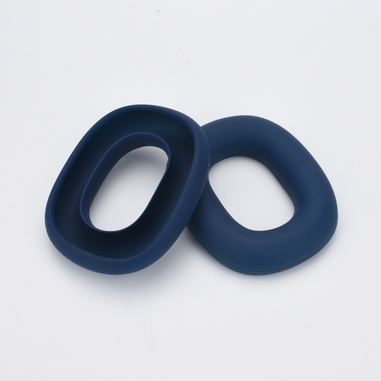 Zwei blaue, oval geformte Ohrpolster. Sie liegen auf einer weißen Oberfläche.