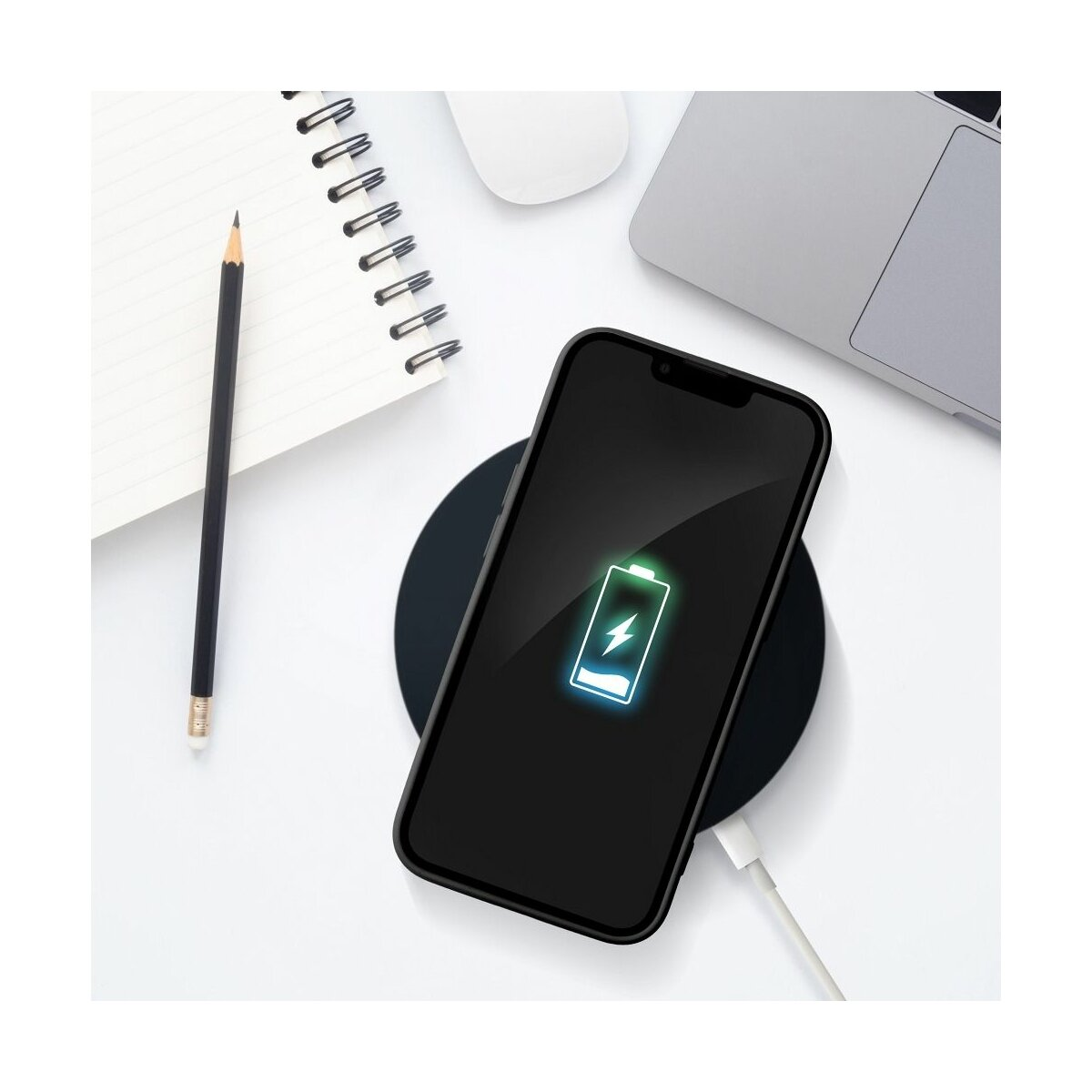 Un telefono nero su un caricatore wireless. Una matita e un blocco note sono anche sul tavolo.