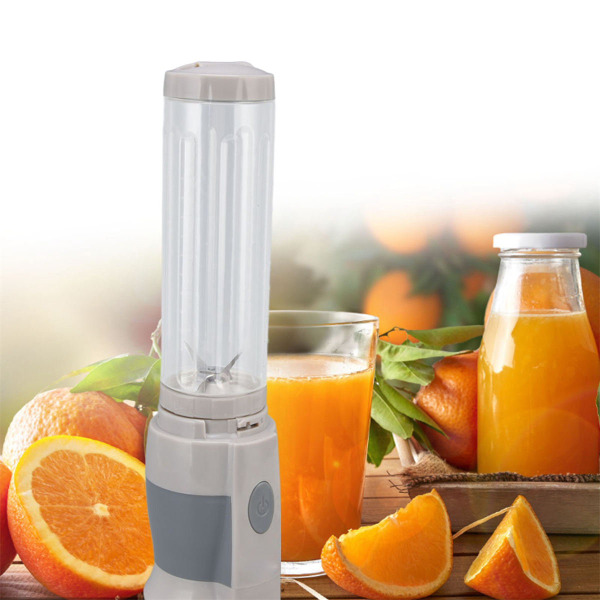 Mixer mit Orangen und Saft. Der Mixer ist grau und weiß. Glas Saft und Orangenscheiben sichtbar.