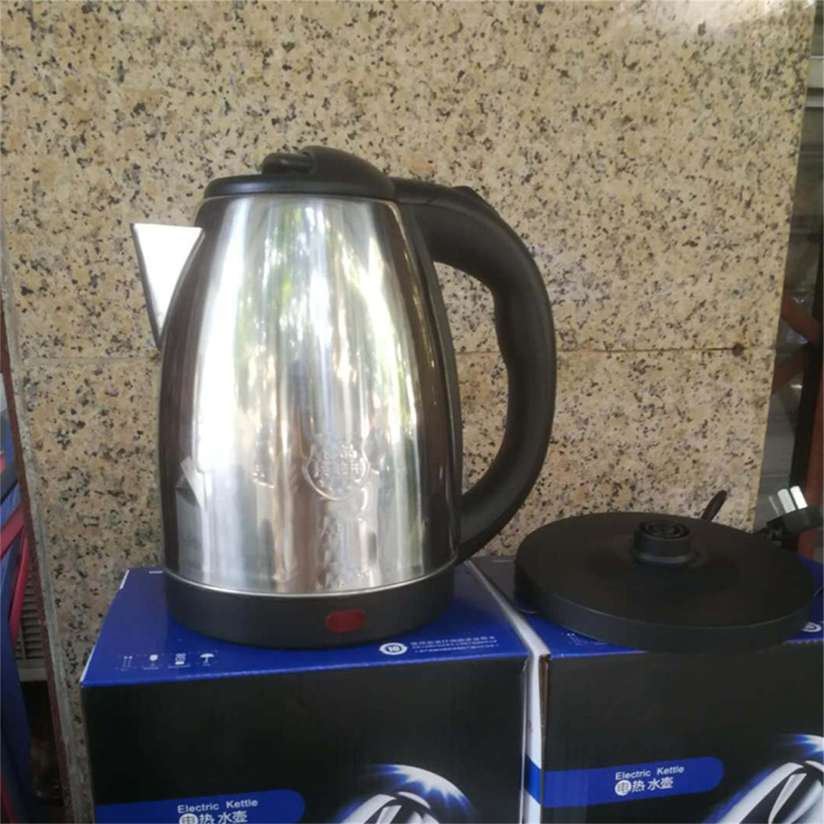 Ein Edelstahl-Wasserkocher mit schwarzem Griff und Deckel.