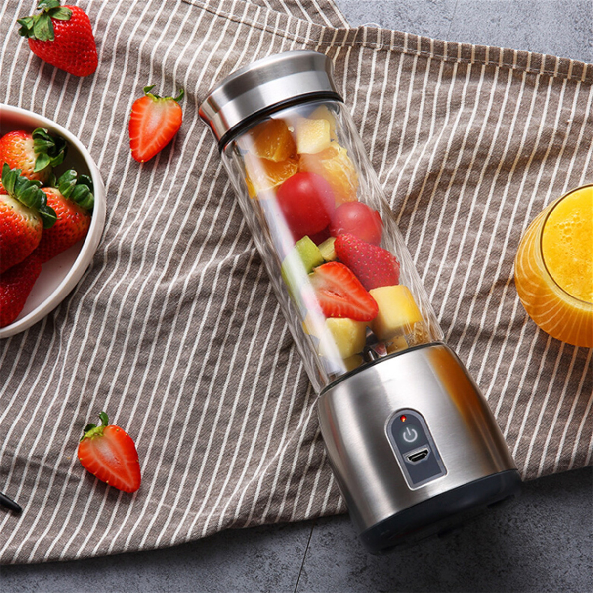 Ein Mixer gefüllt mit Früchten, Erdbeeren, Orangensaft und einem gestreiften Handtuch.
