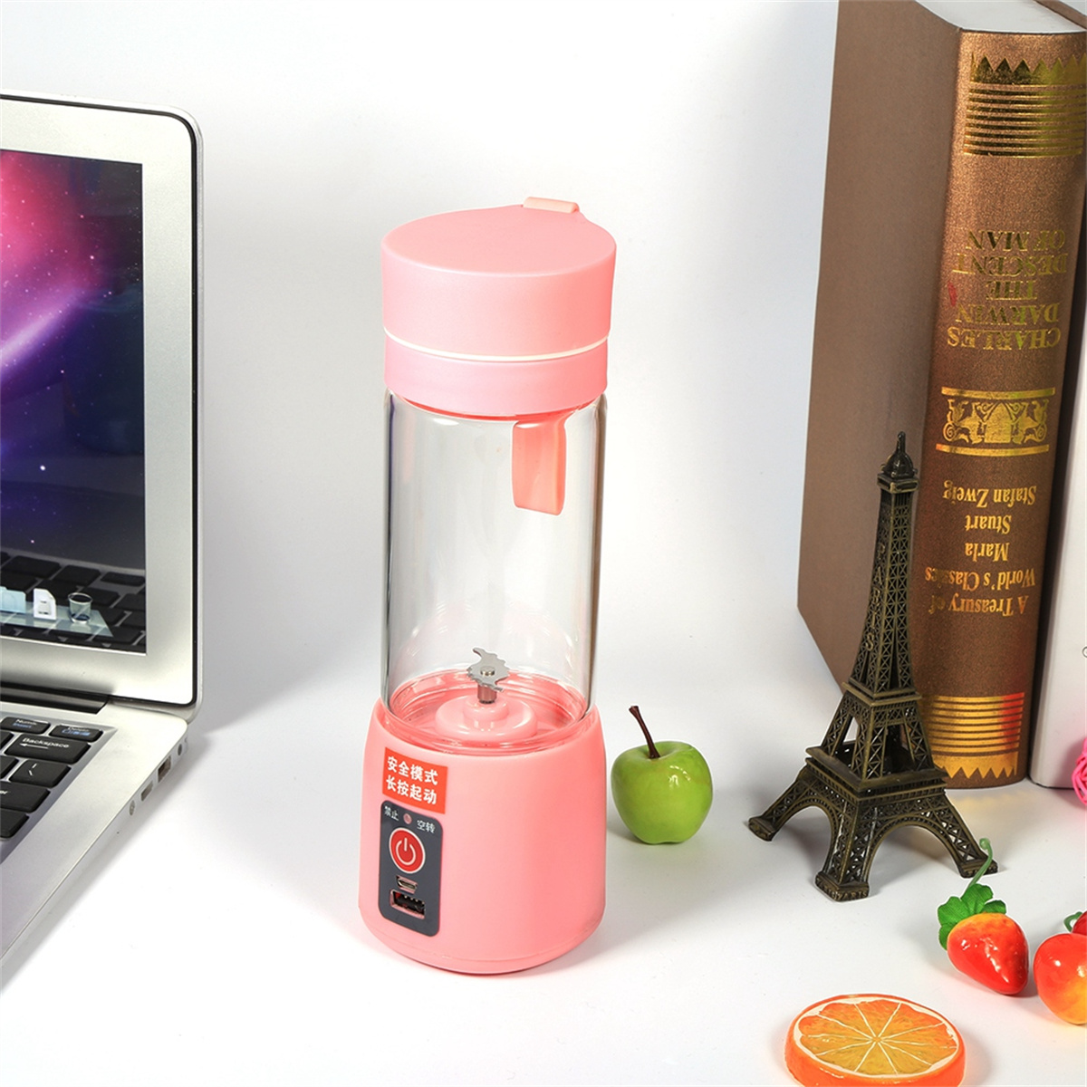 Ein rosa Mixer mit einem transparenten Behälter, einem grünen Apfel und einem Miniatur-Eiffelturm.