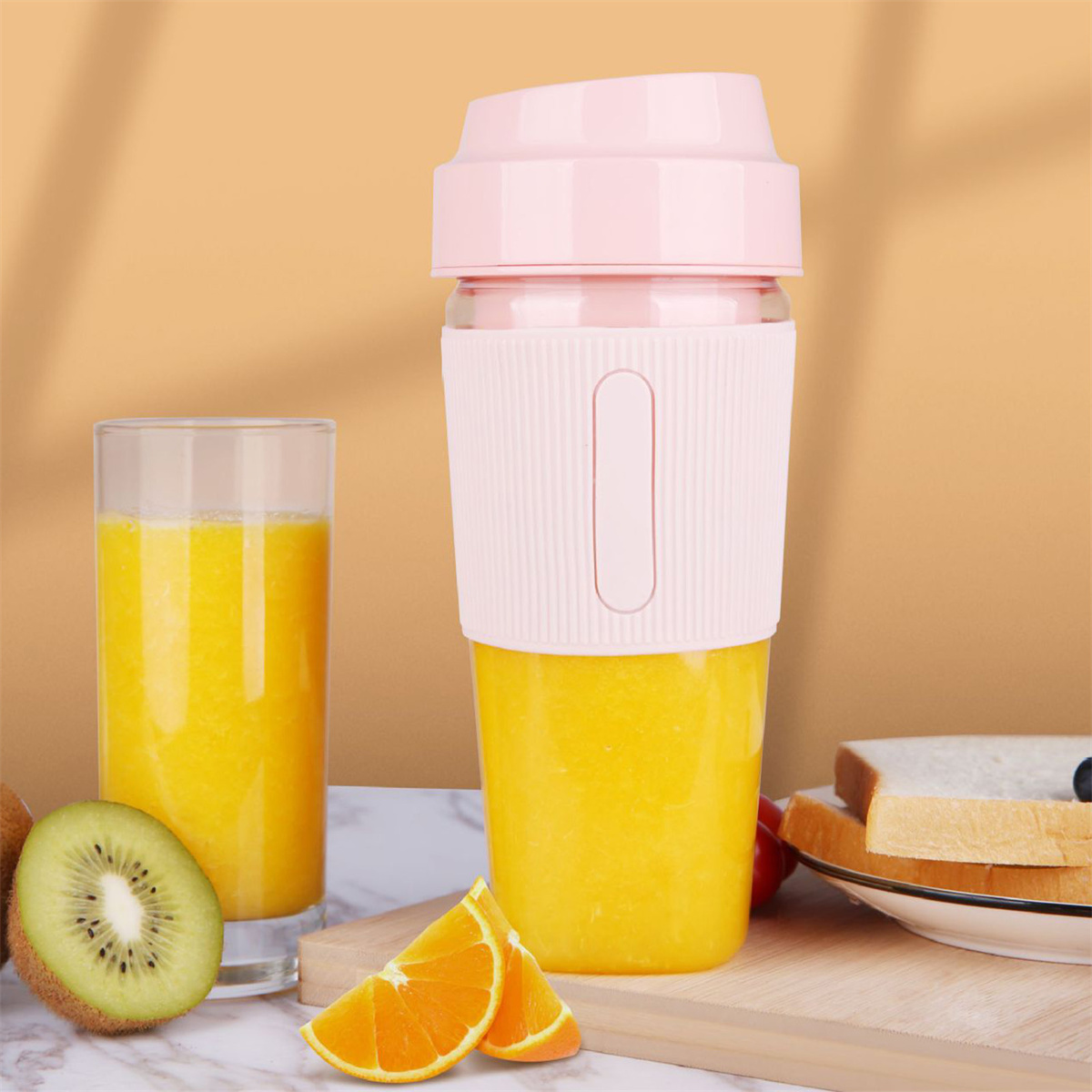 Rosa und klarer Mixer mit Orangensaft, Kiwi und Orangenscheiben. Ein Glas Orangensaft in der Nähe.
